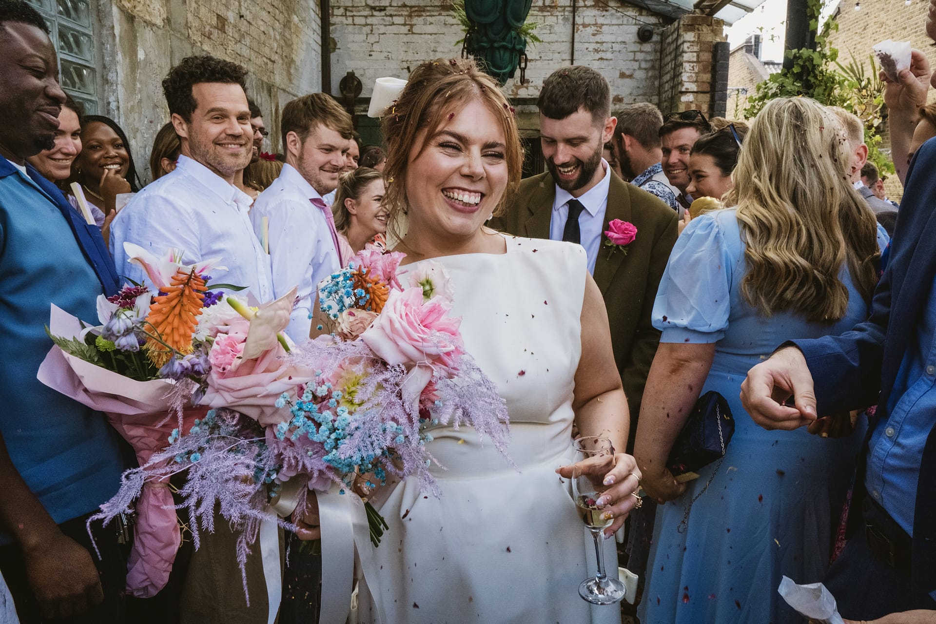 Happy bride holding bouquet among smiling guests.