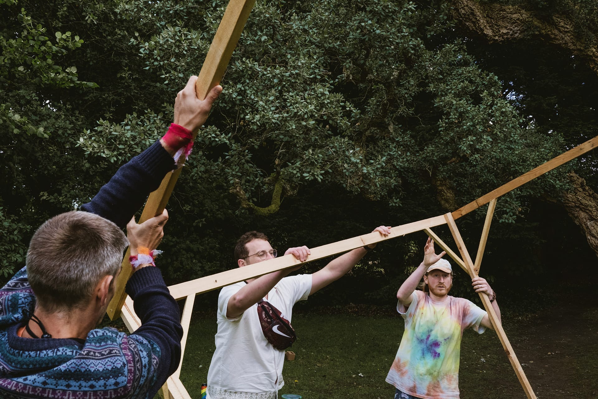 People assembling wooden structure outdoors