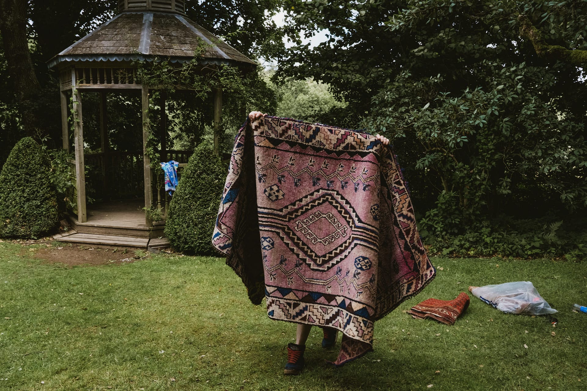 Person playing with large pink patterned blanket outside.