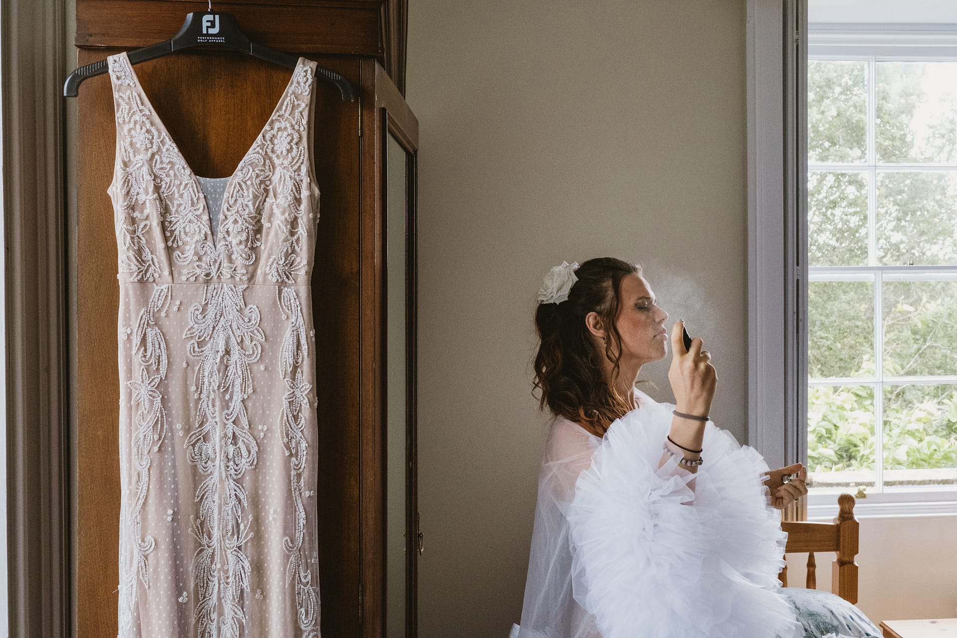 Bride getting ready beside her wedding dress.