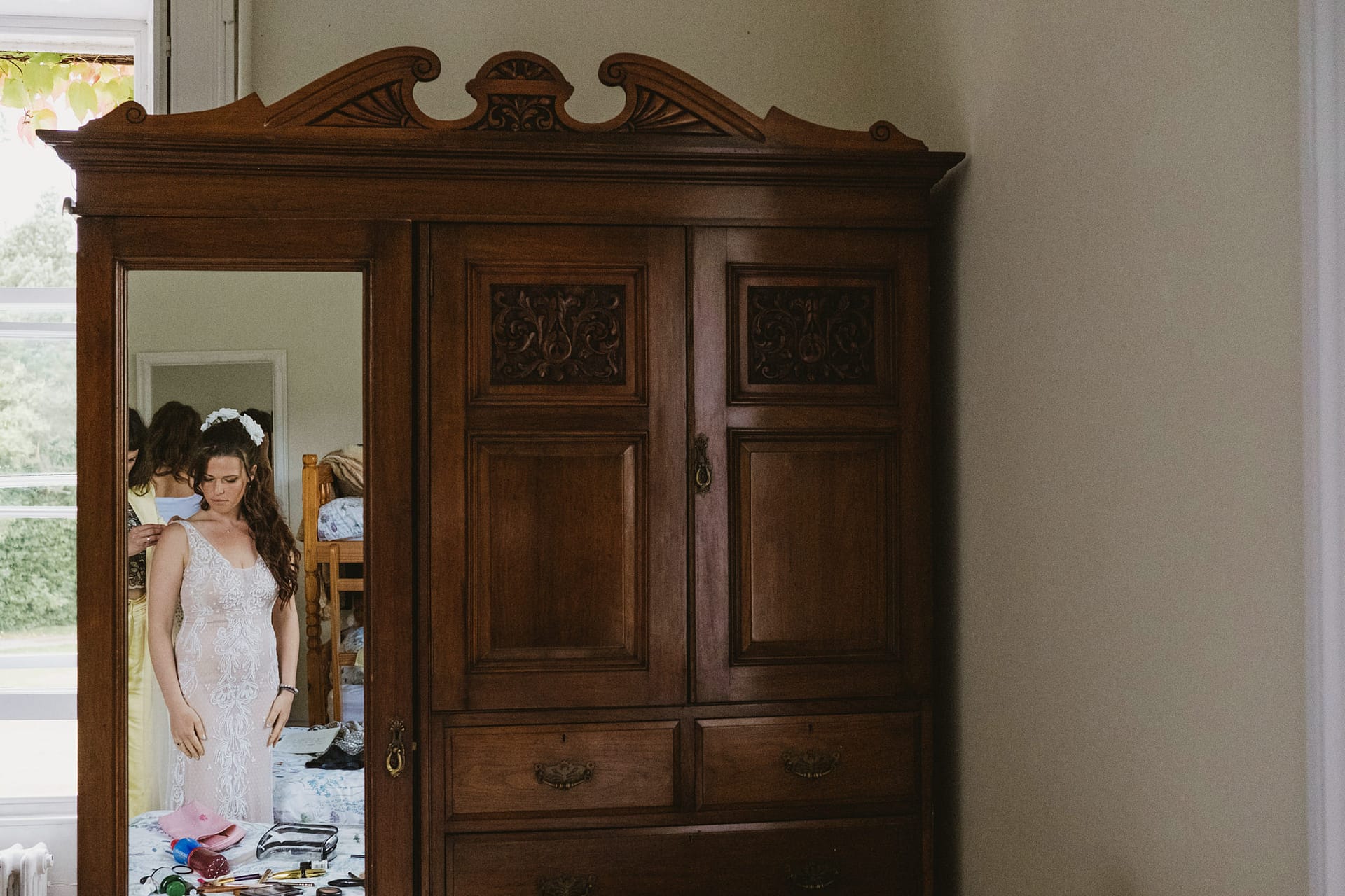 Bride reflected in wardrobe mirror, dressing preparation.