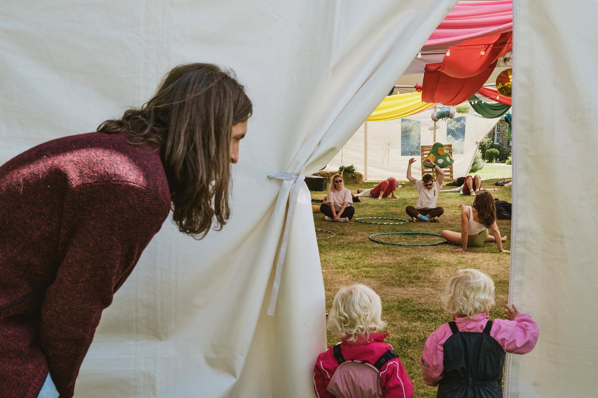 Children peering into a colourful yoga tent
