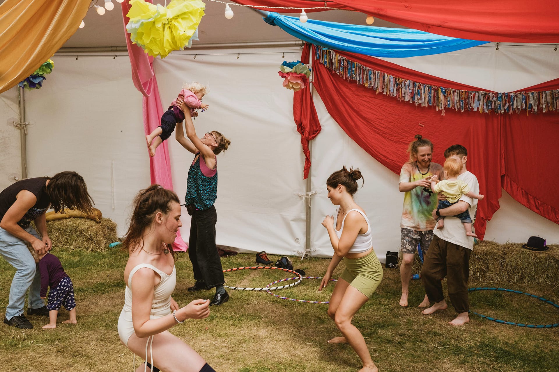 People with children playing in vibrant tent.