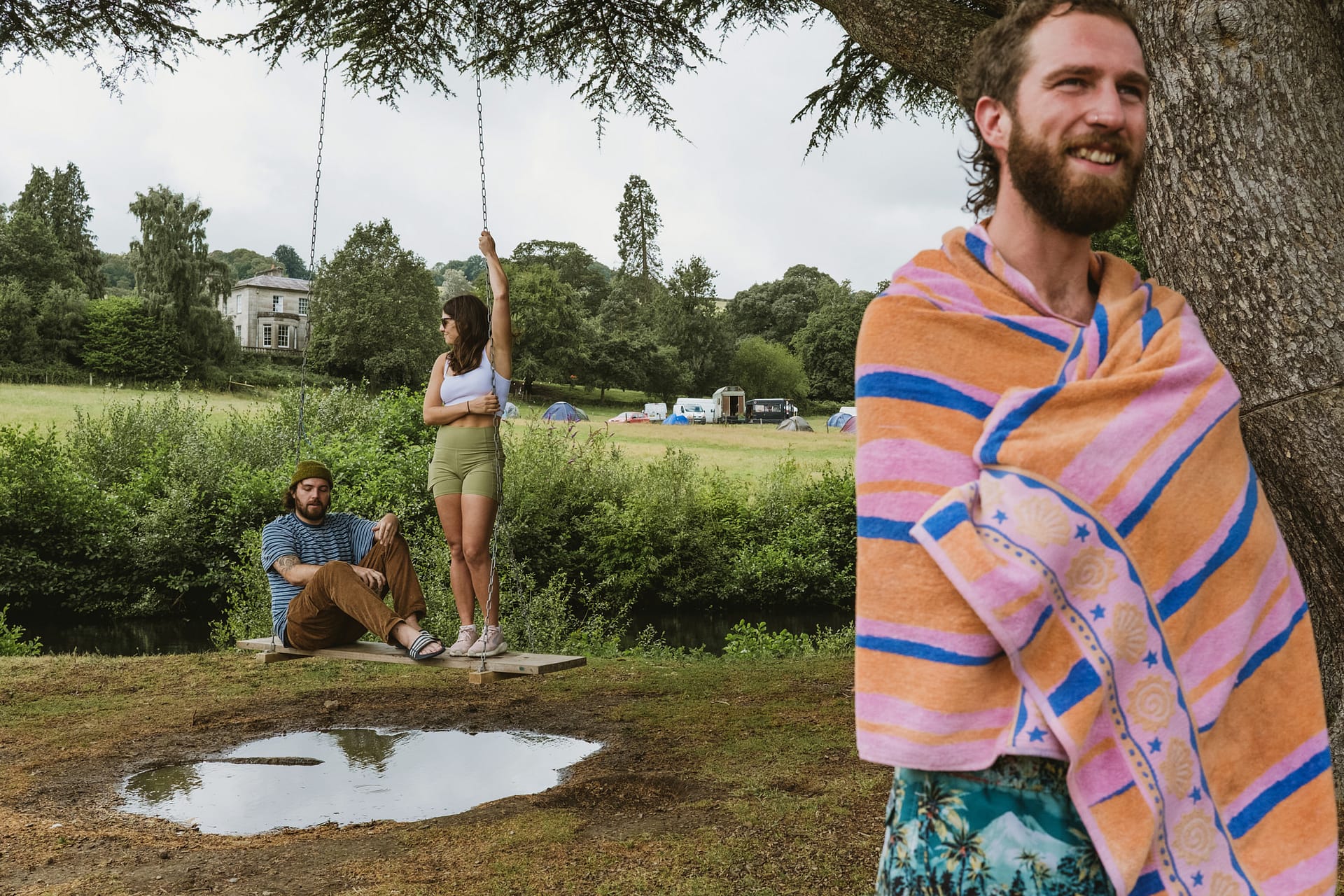 Three people outdoors by a swing and tree.