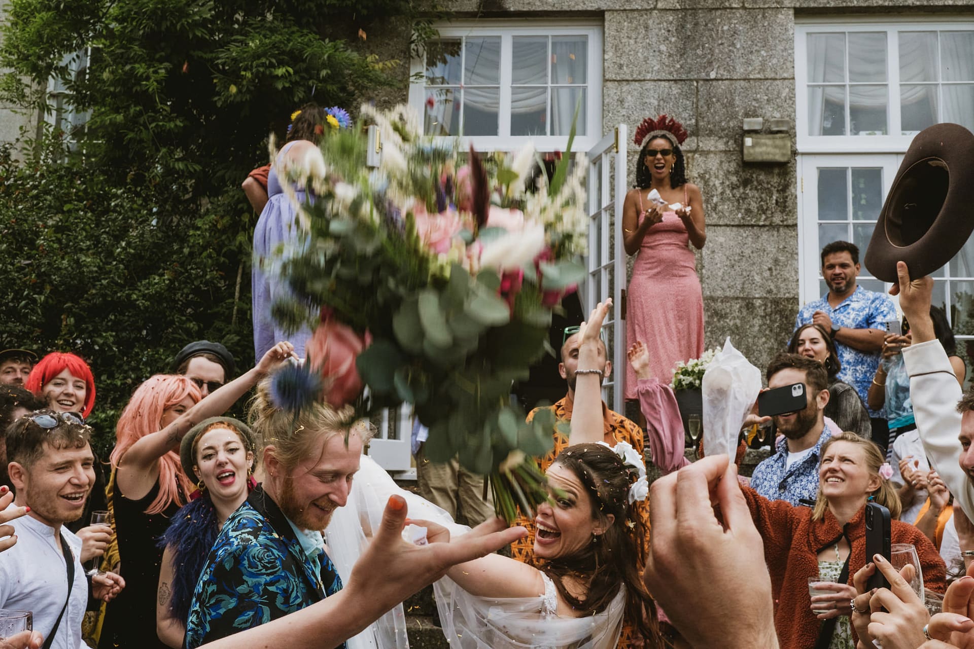Wedding bouquet toss with guests celebrating.
