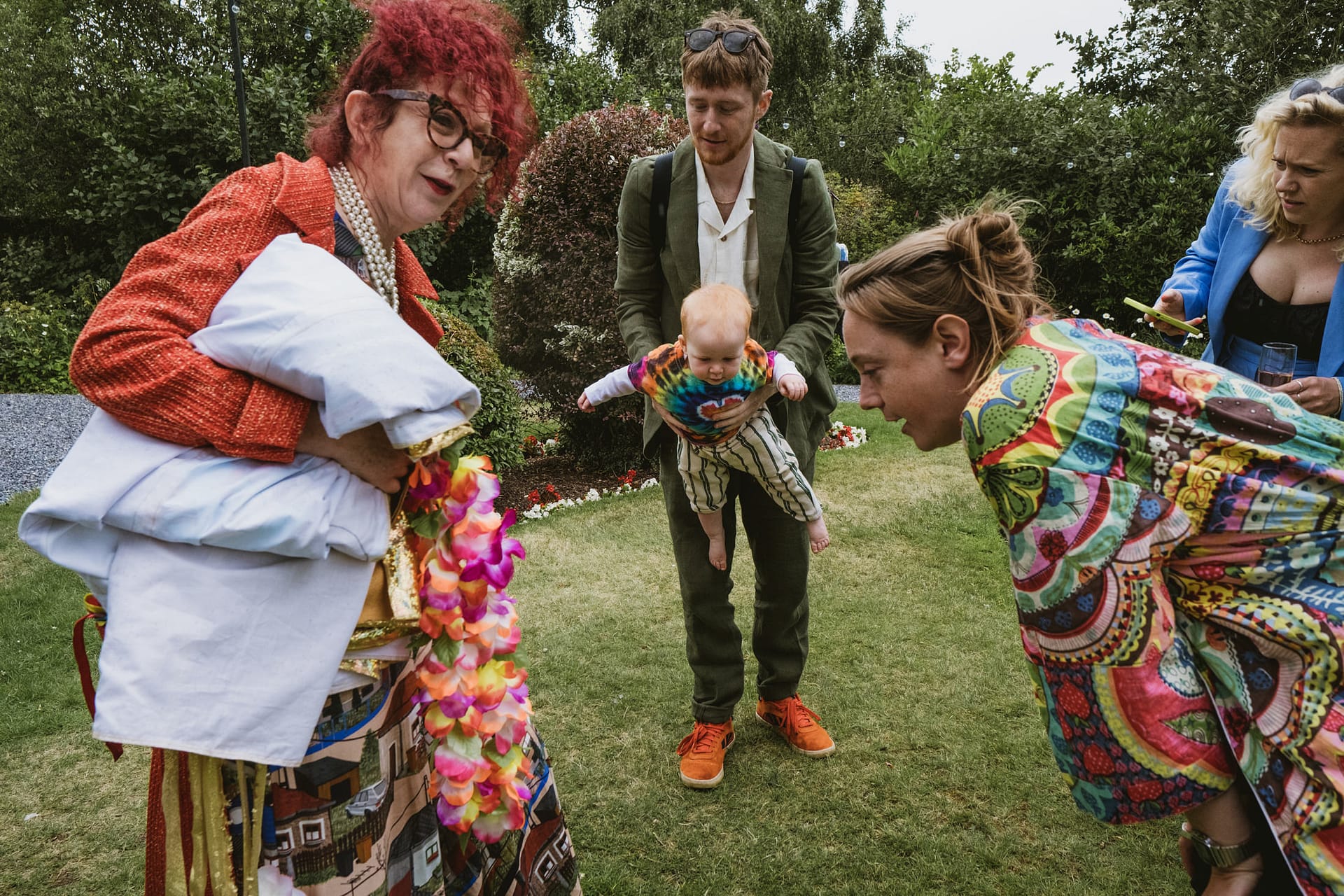 People interacting outdoors with baby and colourful attire.