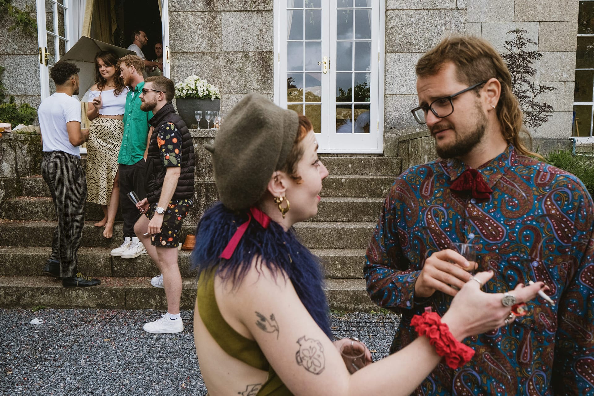 People socialising at outdoor party near stone steps.