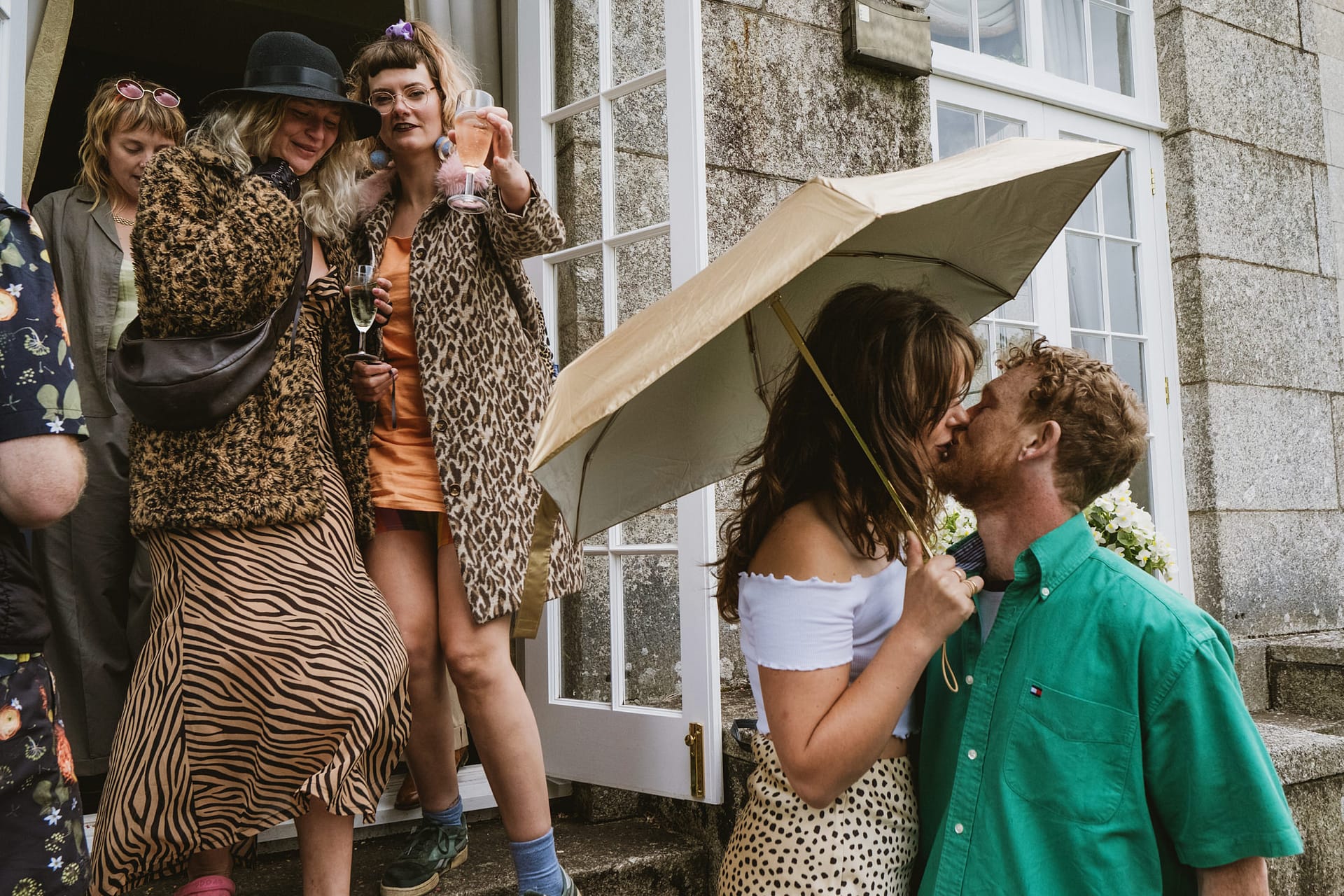People at a party, kissing under umbrella