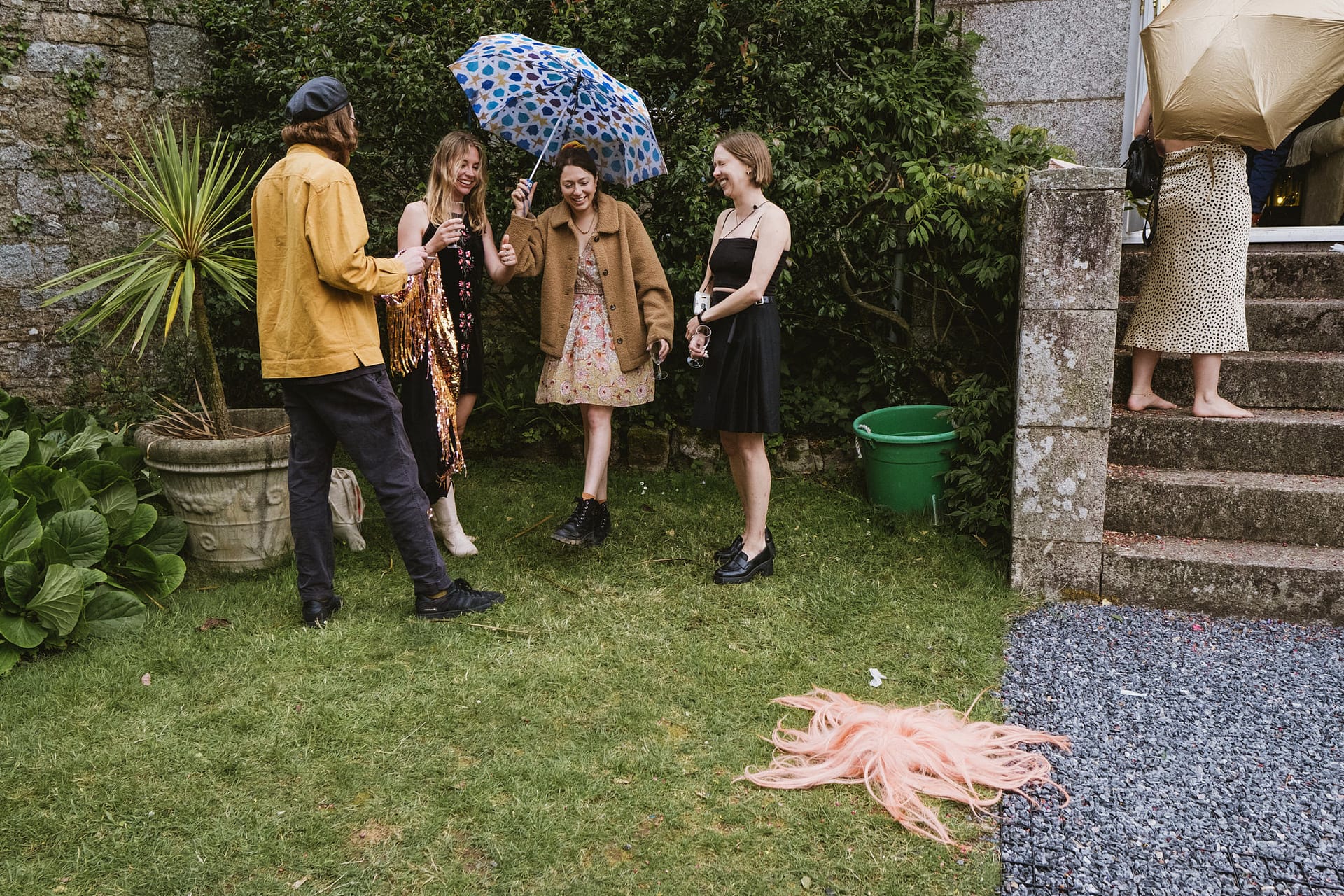 People standing with umbrellas in garden.