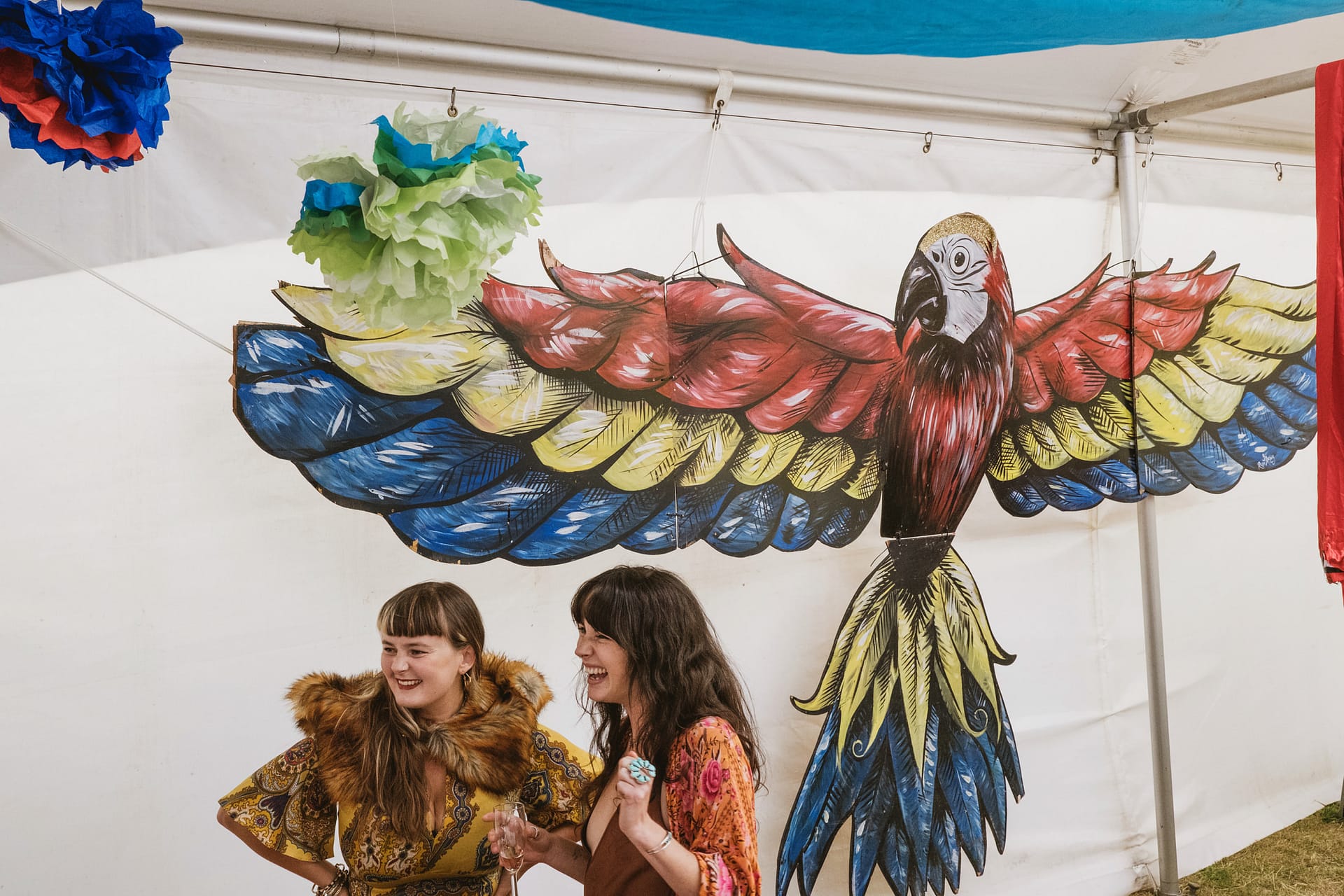 Women laughing in front of parrot mural.