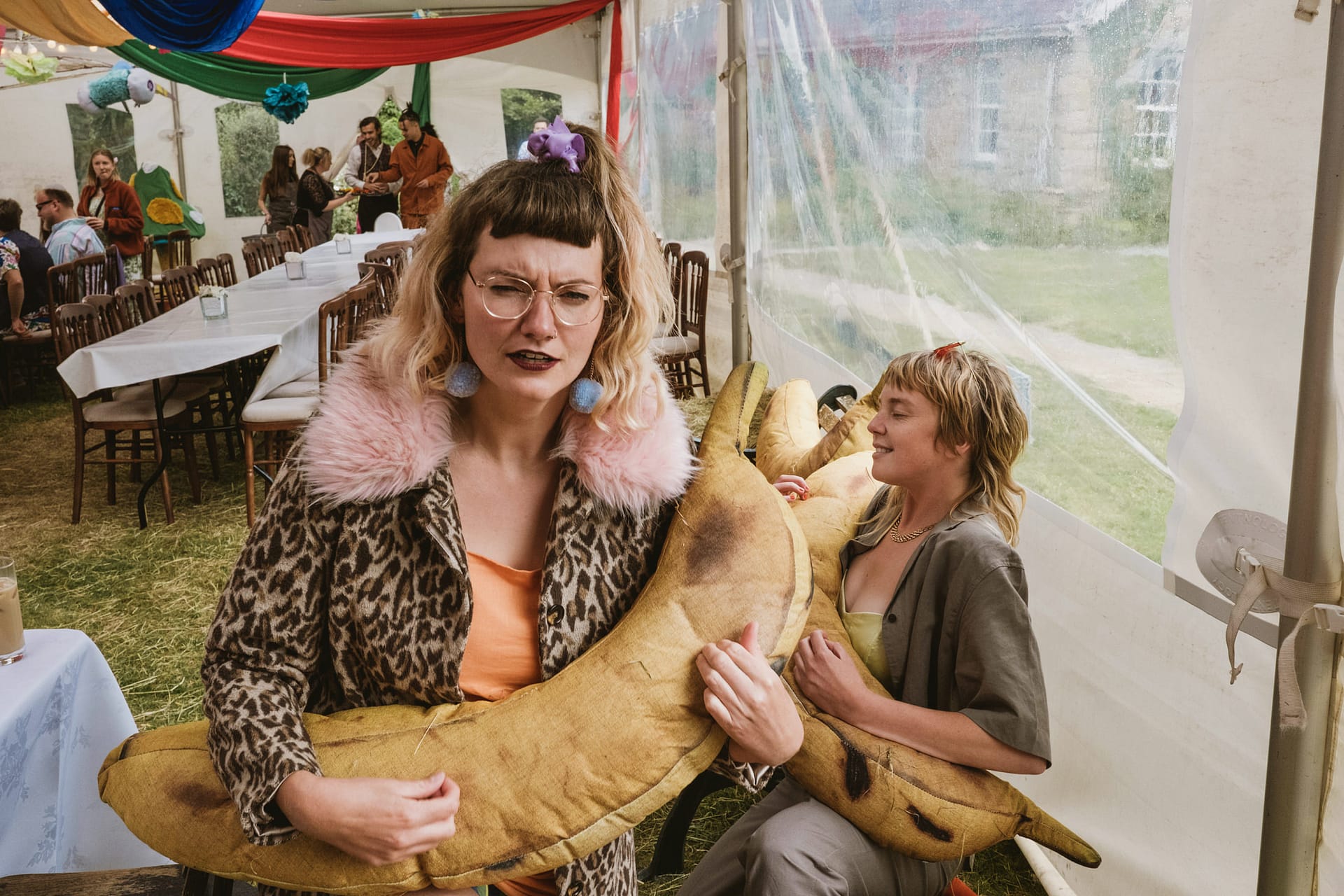 People holding oversized banana plush toys at a party.