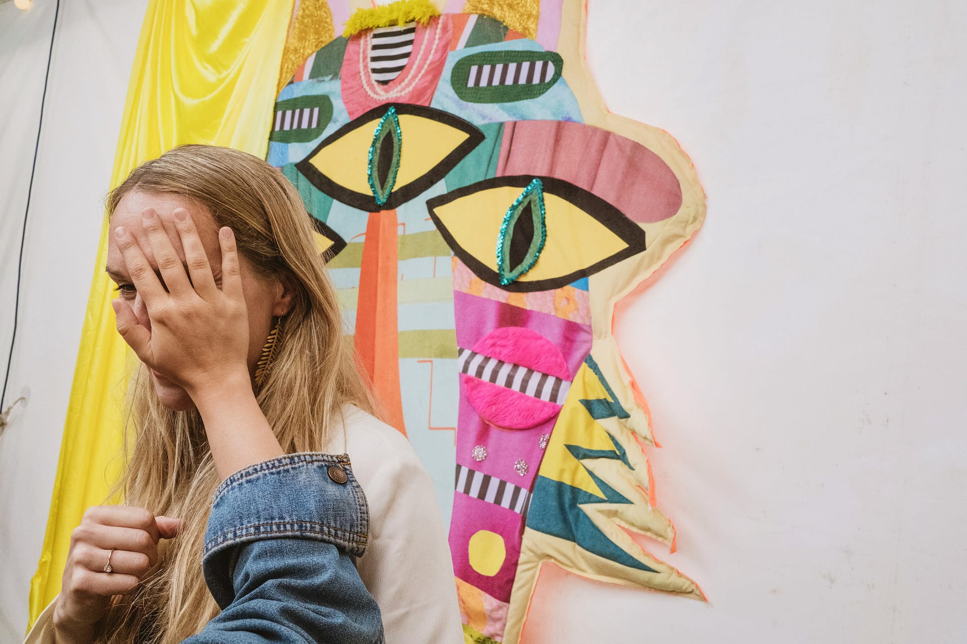 Woman covering face with hand near colourful decoration.