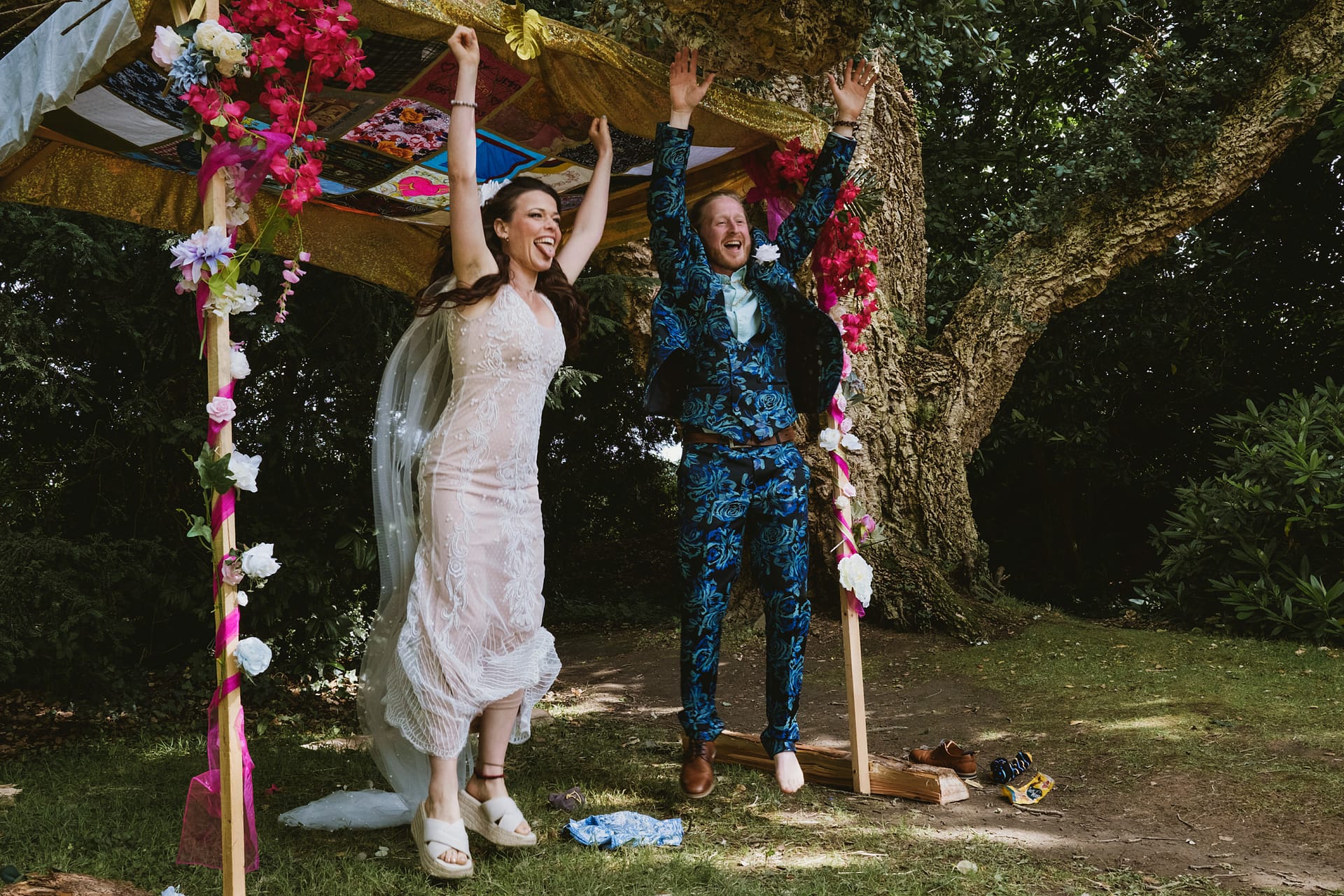 Newlyweds celebrating under a colourful canopy outdoors.