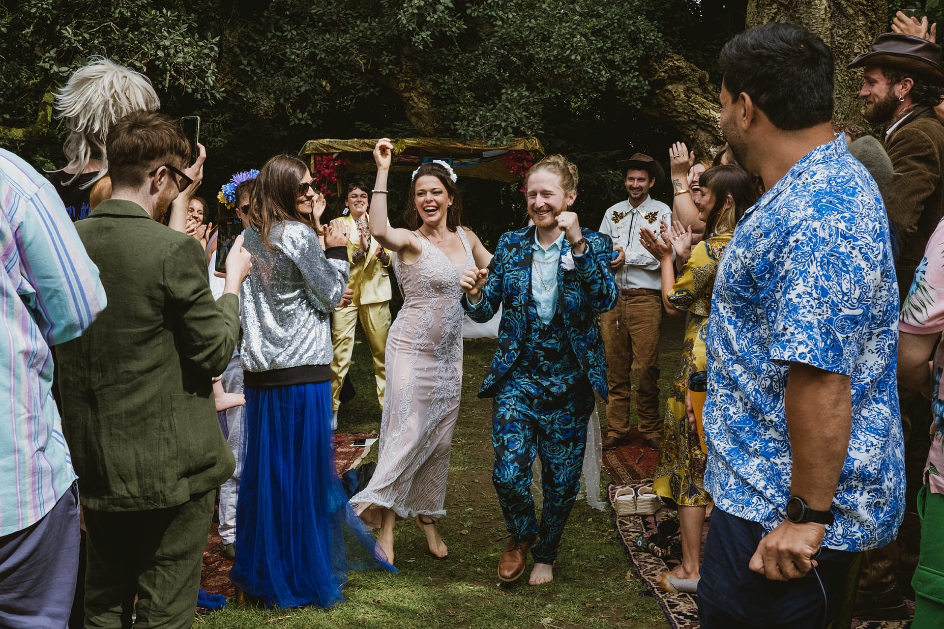 Joyful wedding celebration with dancing guests outdoors.