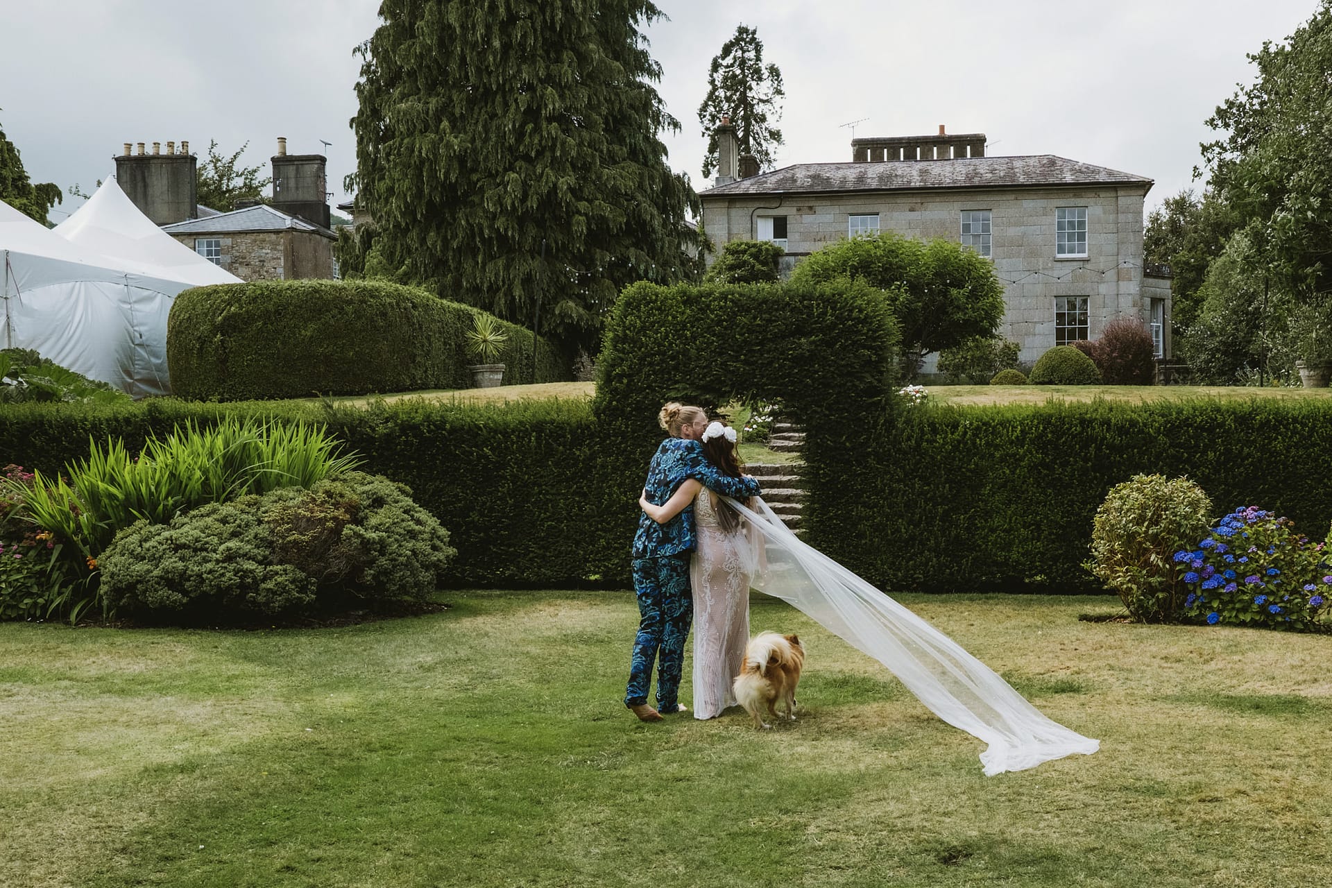 Couple embracing in Colehayes Park's garden with dog
