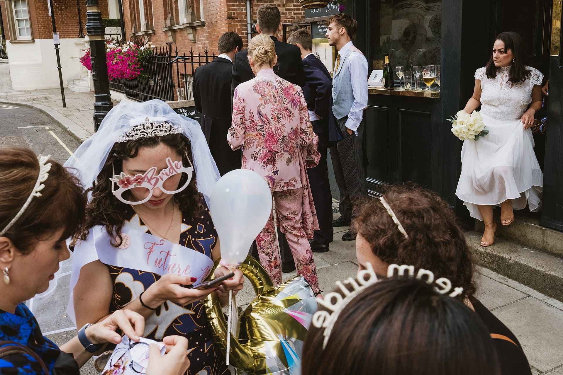bride leaving the pub surrounded by a hen party and a bride to be