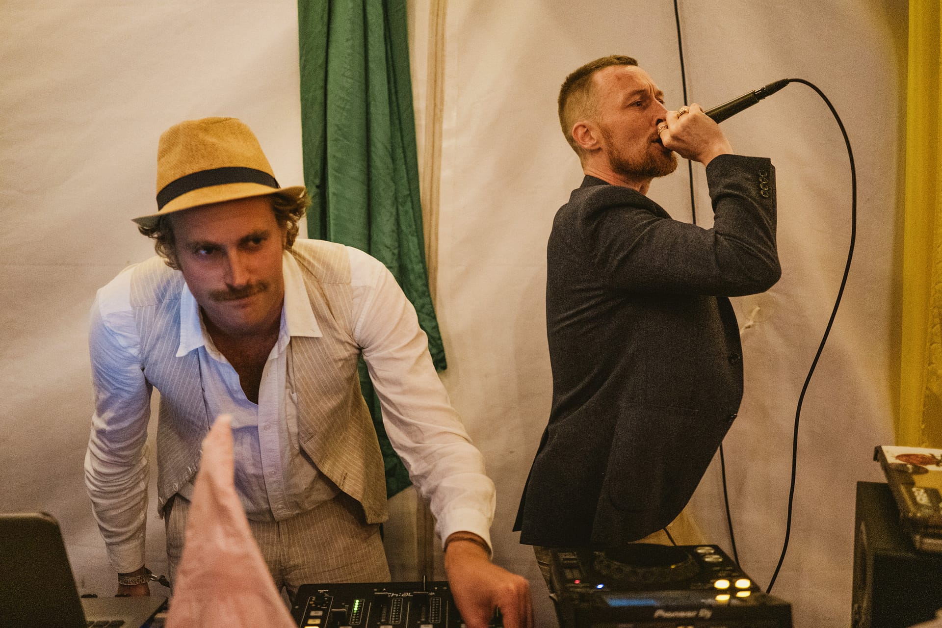 Two musicians performing, one DJing, one singing.