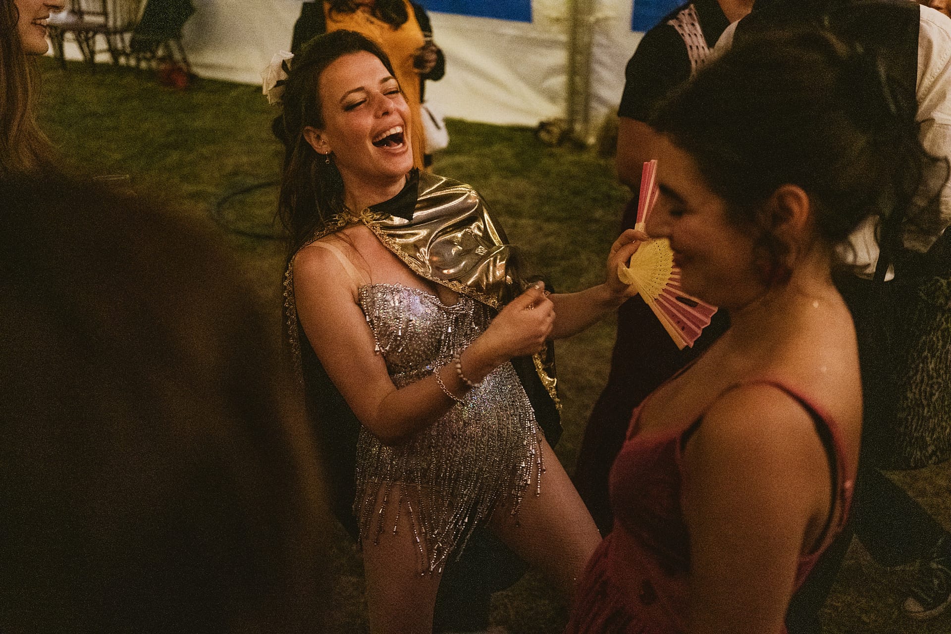 Woman laughing at a party in glamorous outfit.