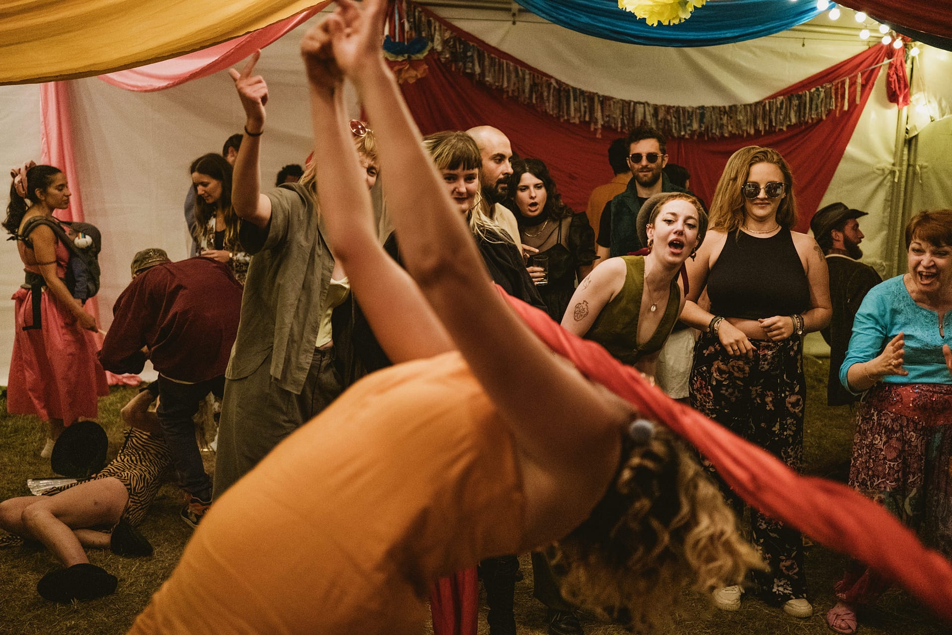 People dancing under colourful drapes at a party.