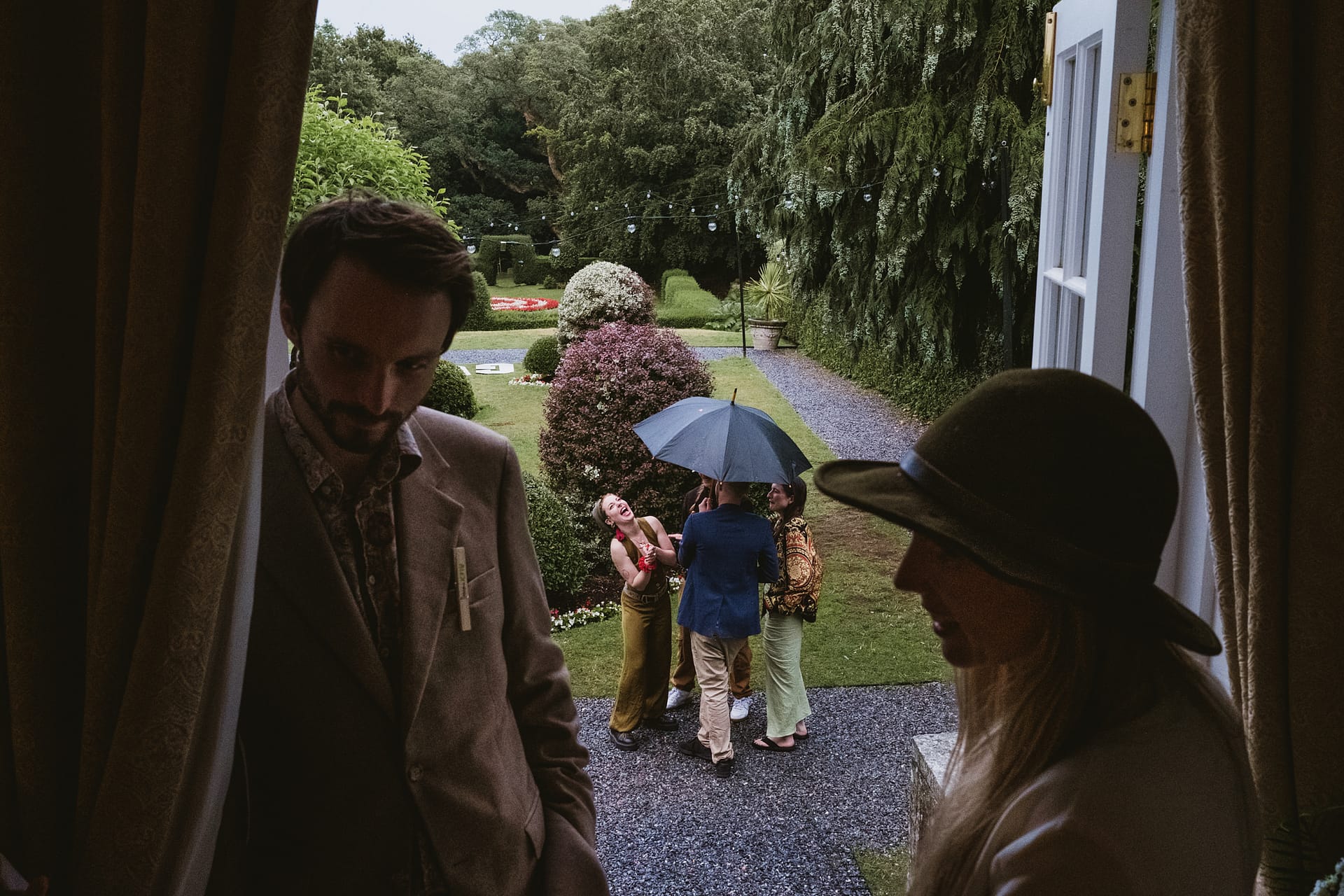 People enjoying a garden party under umbrellas.