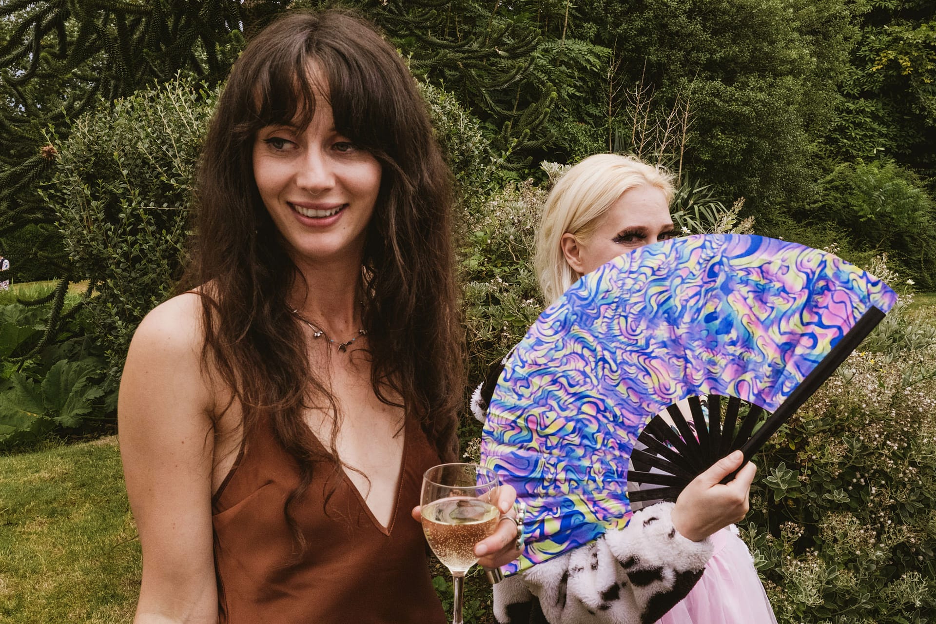 Women outdoors with fan and wine glass