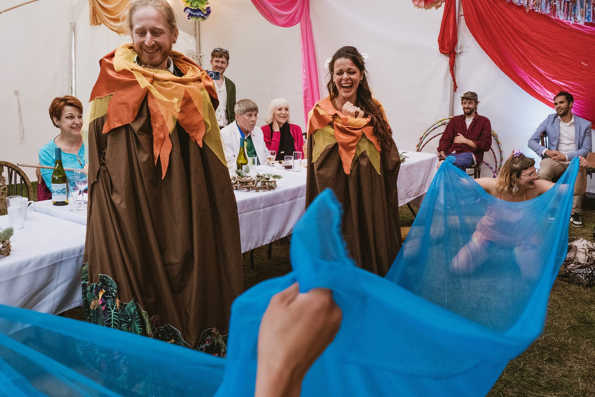 People in costumes and blue fabric at a celebration.