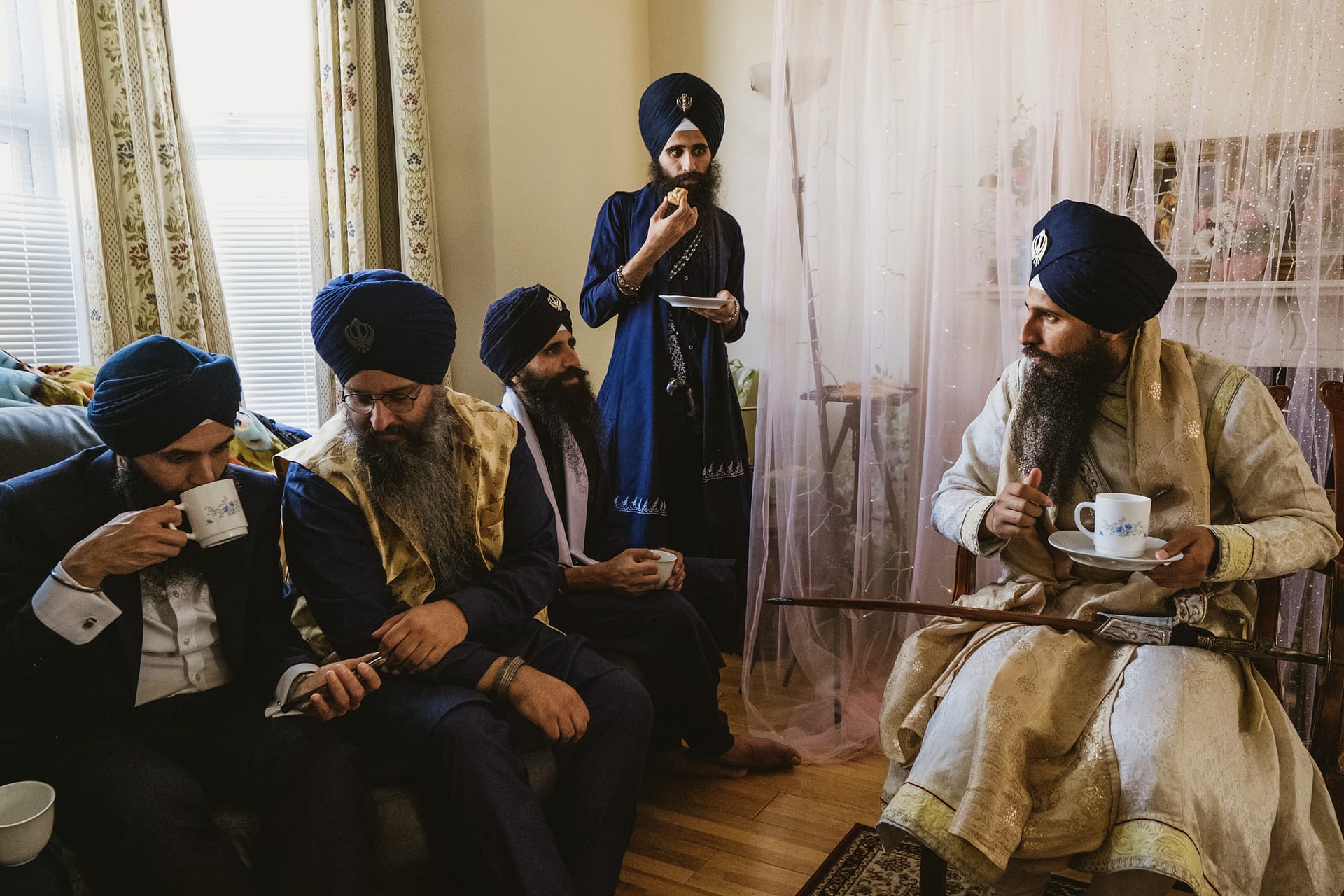 Sikh men enjoying tea and conversation indoors.