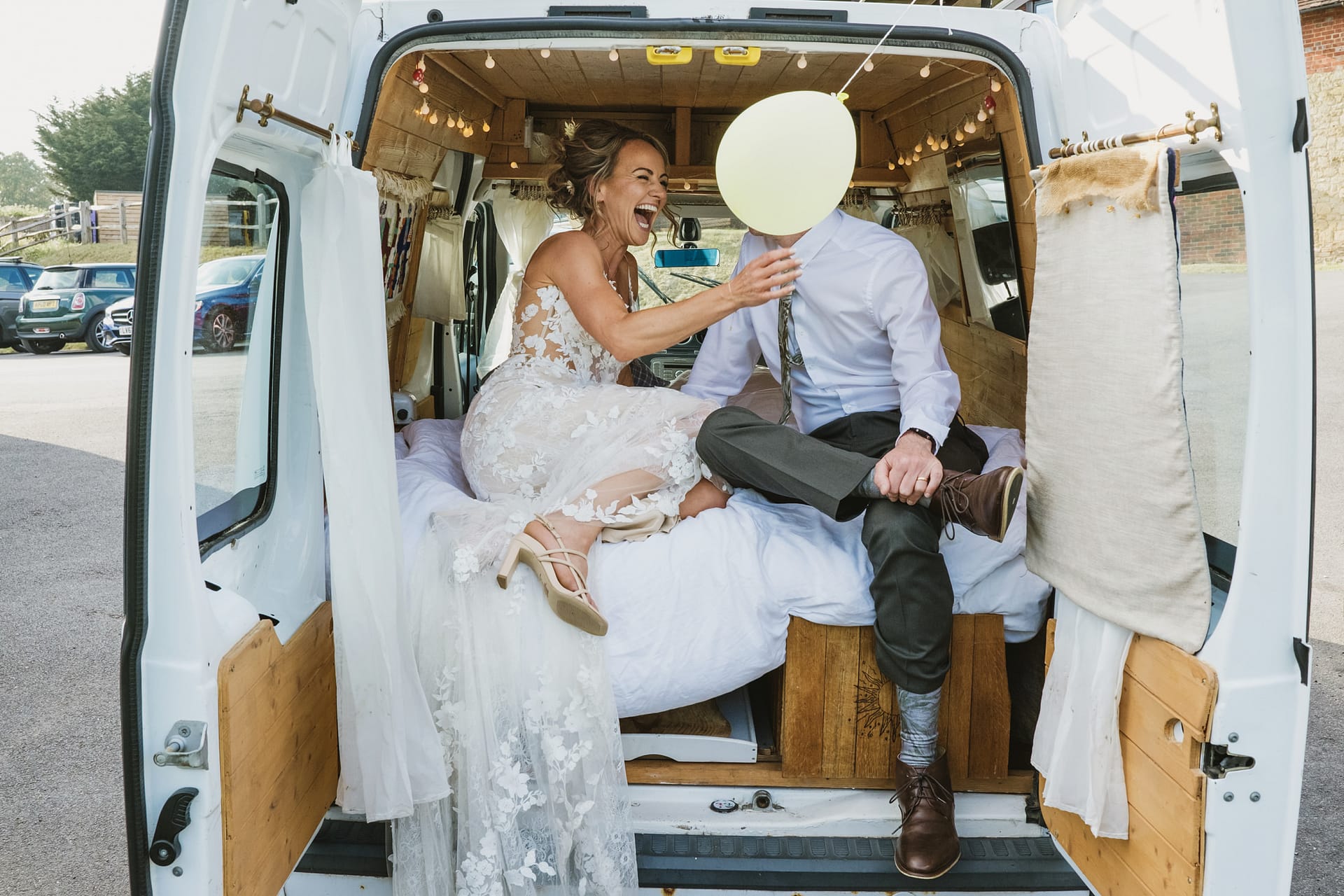 Couple laughing inside camper van on their wedding