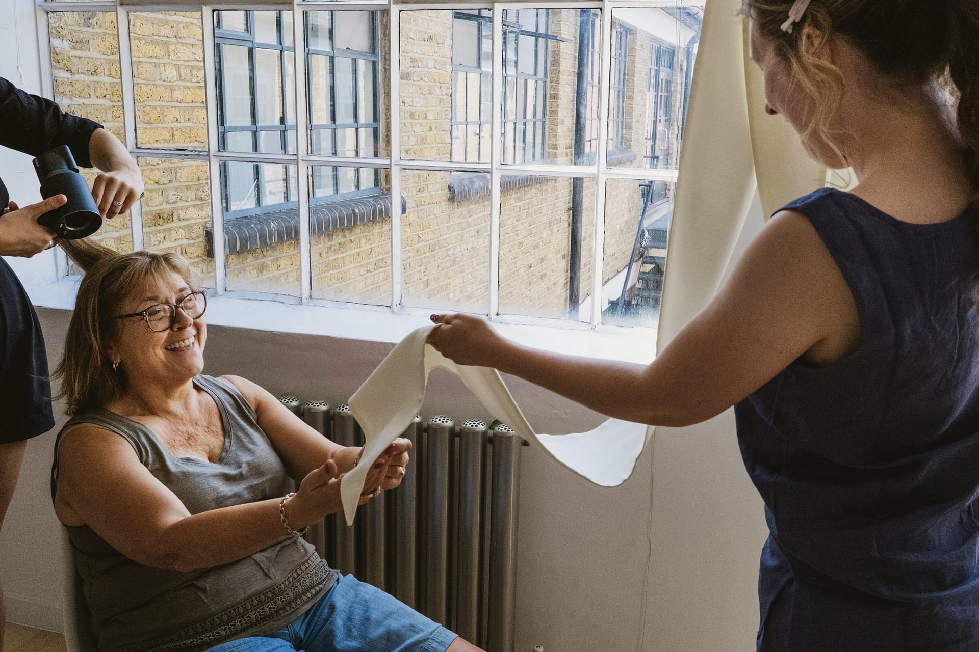 Woman getting hair blow-dried and reading paper.