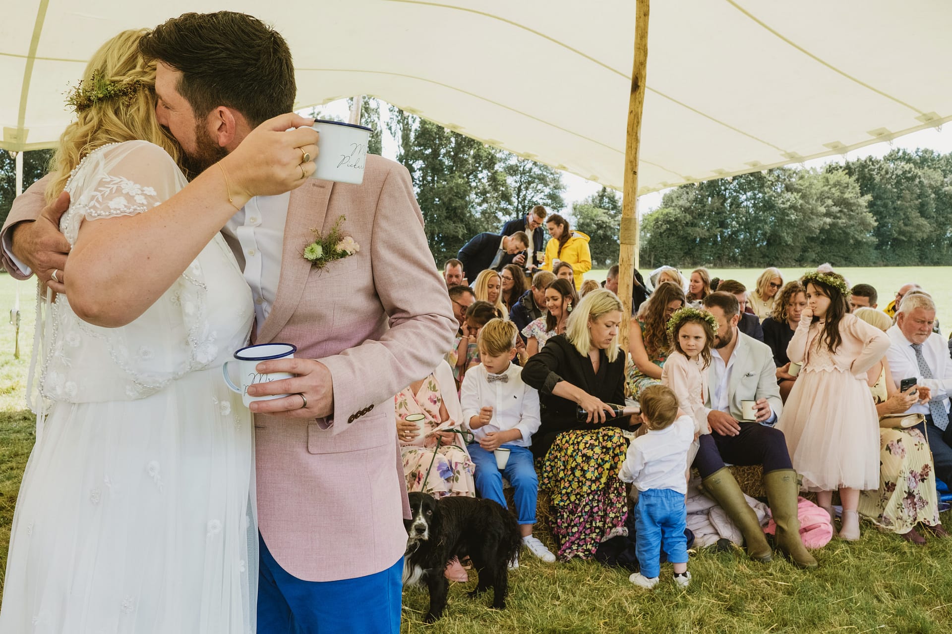 Newlyweds kiss at outdoor wedding ceremony with guests.