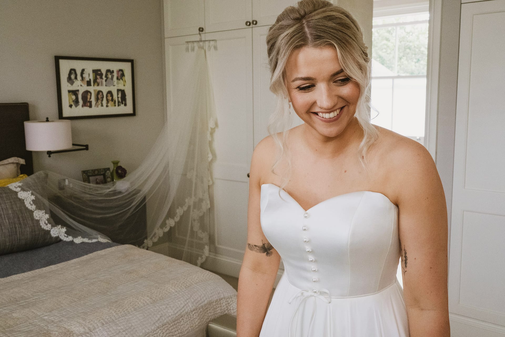 Smiling bride in wedding dress, bedroom setting.
