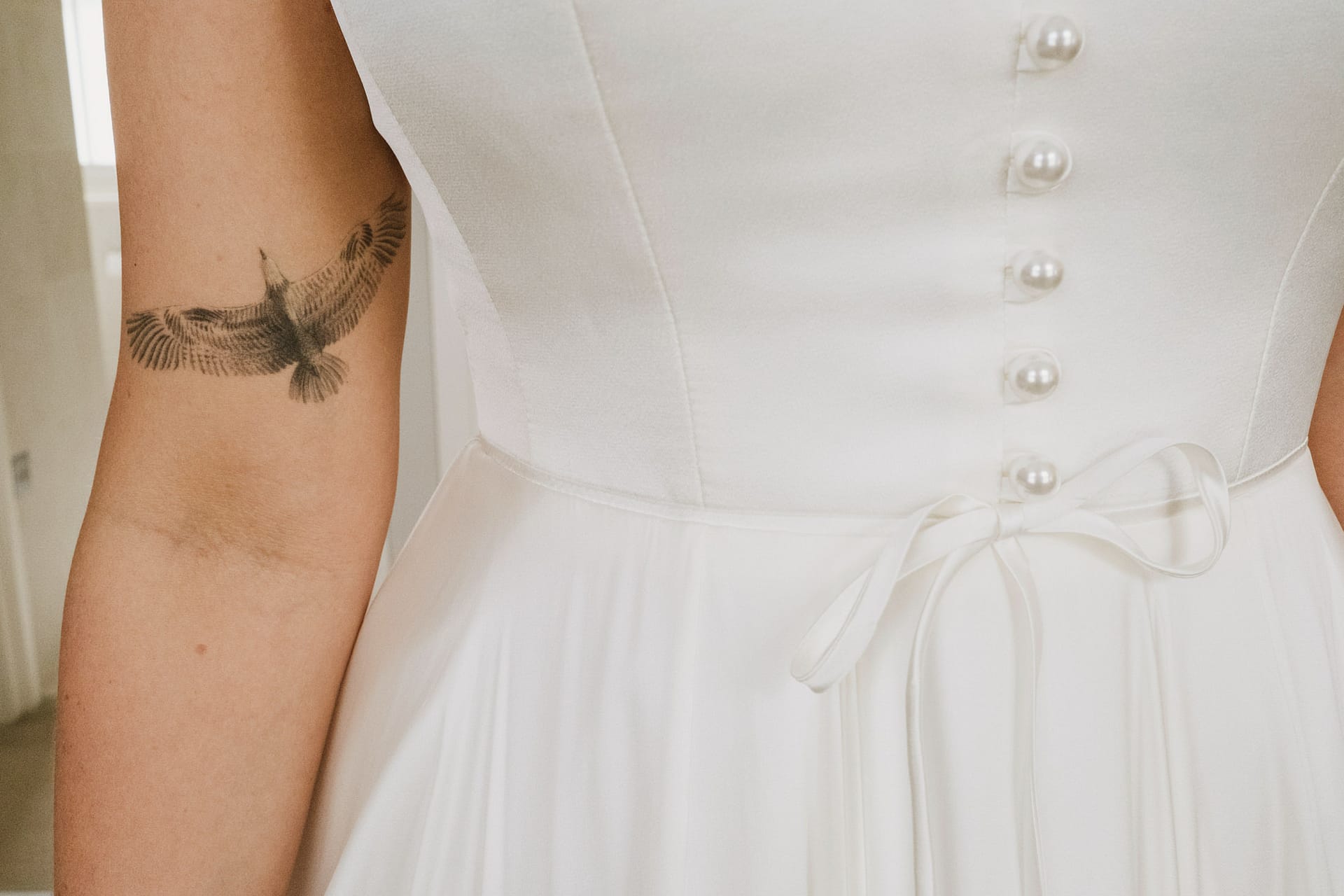 Bride's dress with bird tattoo on arm