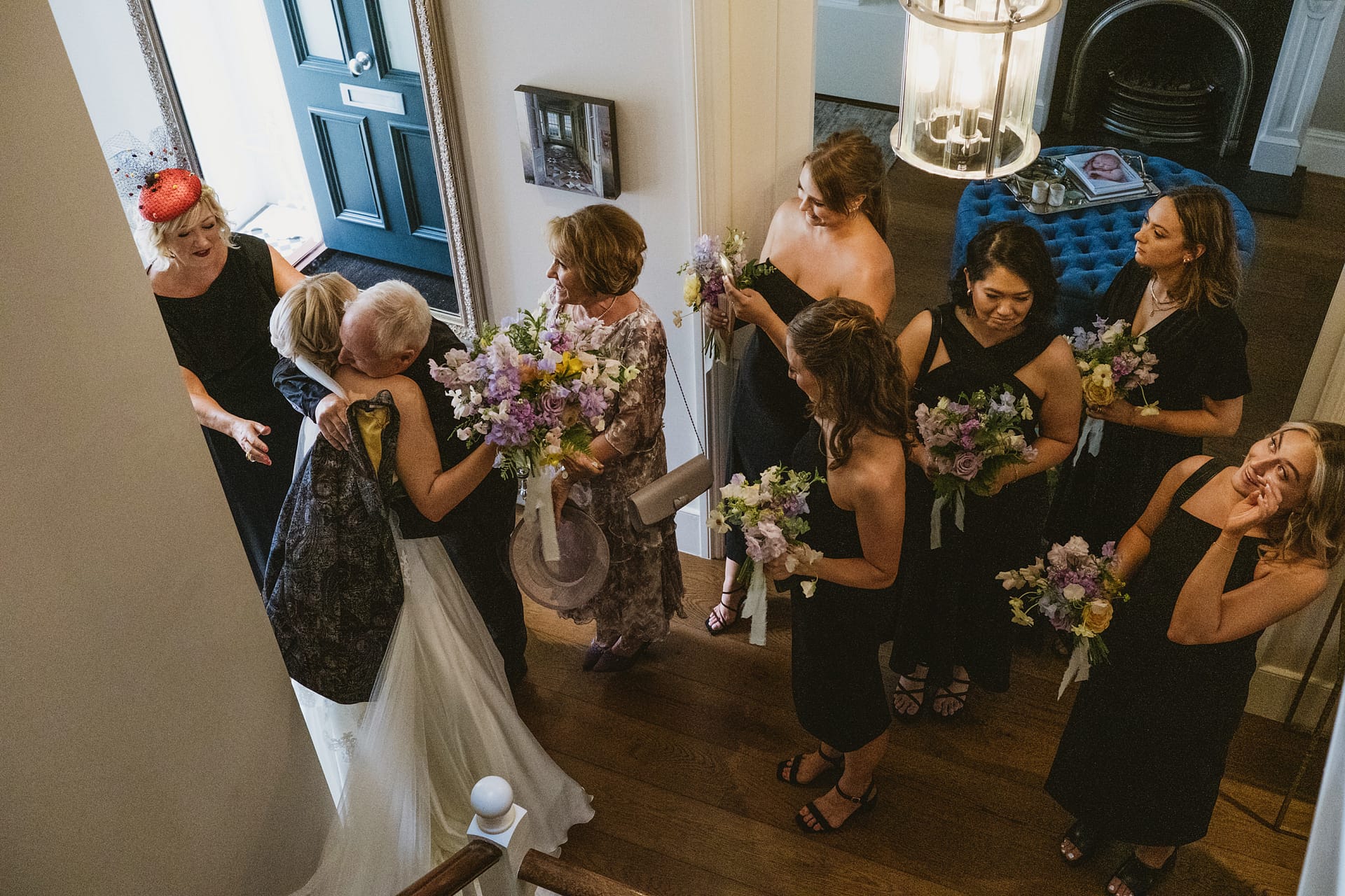 Wedding party gathering with bouquets in hallway.