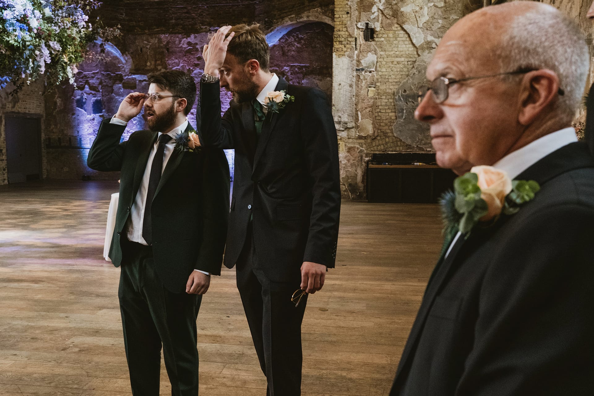Men in suits at a rustic wedding venue.