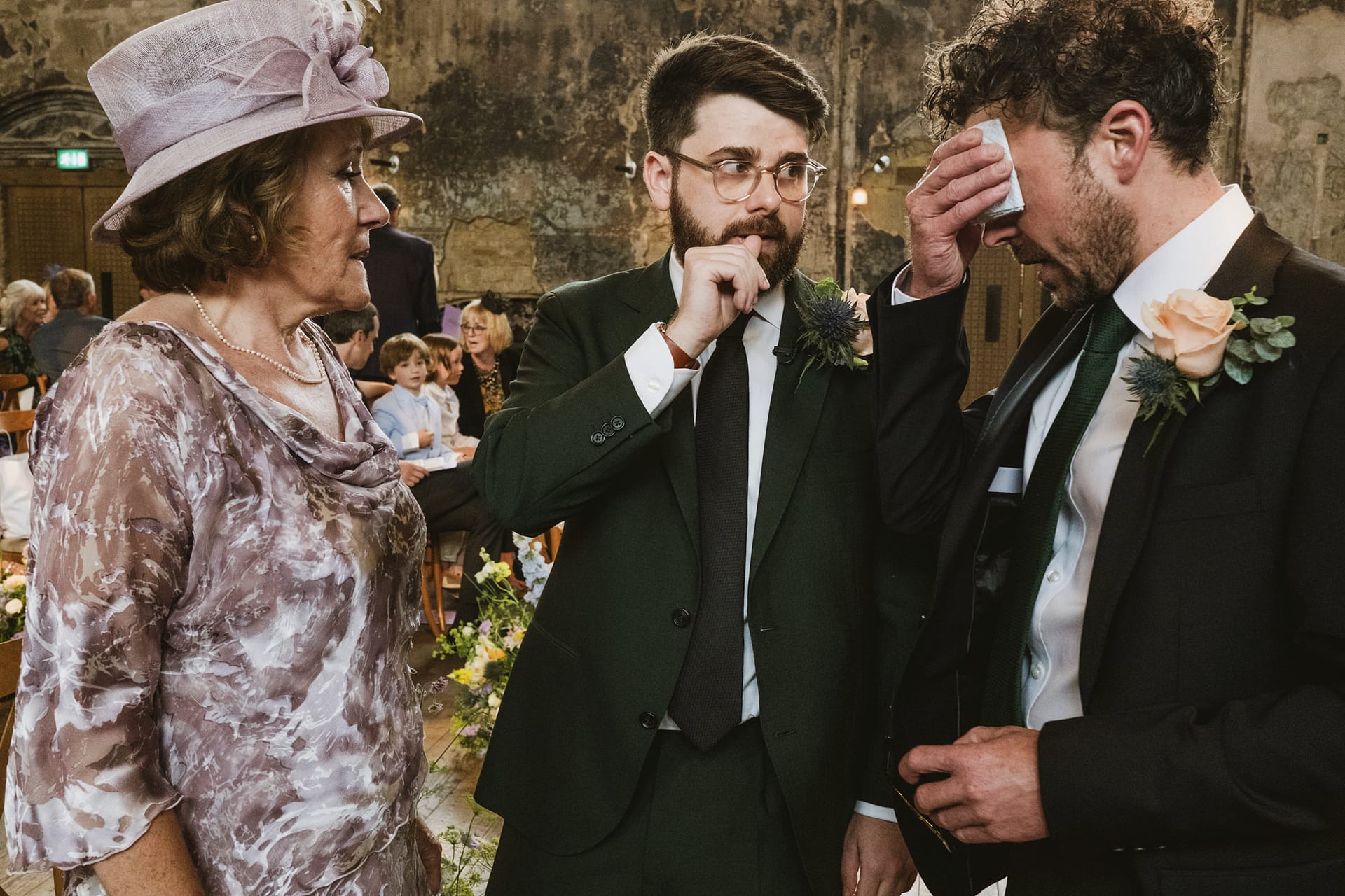Emotional wedding moment between three elegantly dressed people.