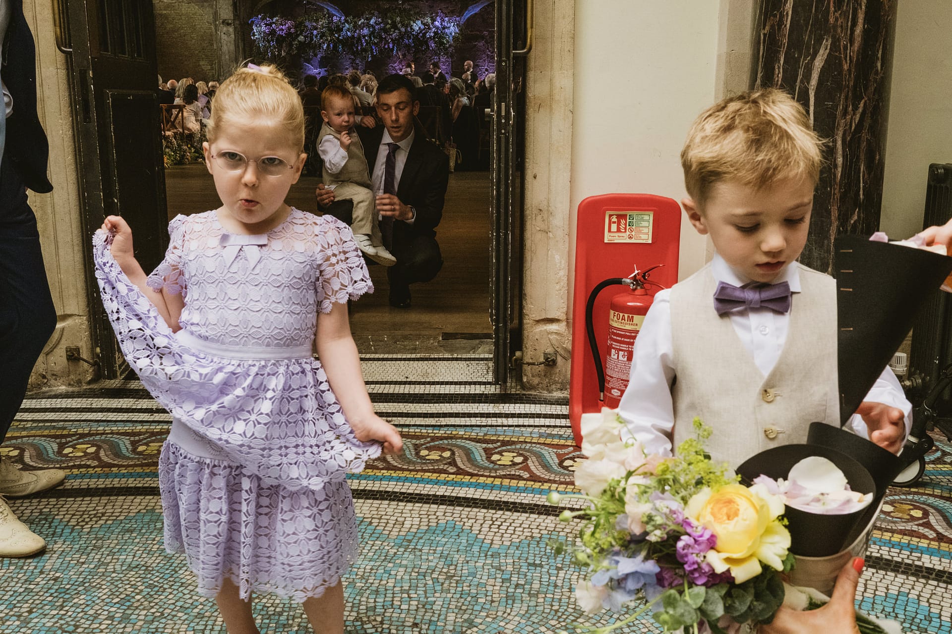 Children in formal wear with flowers at an event.