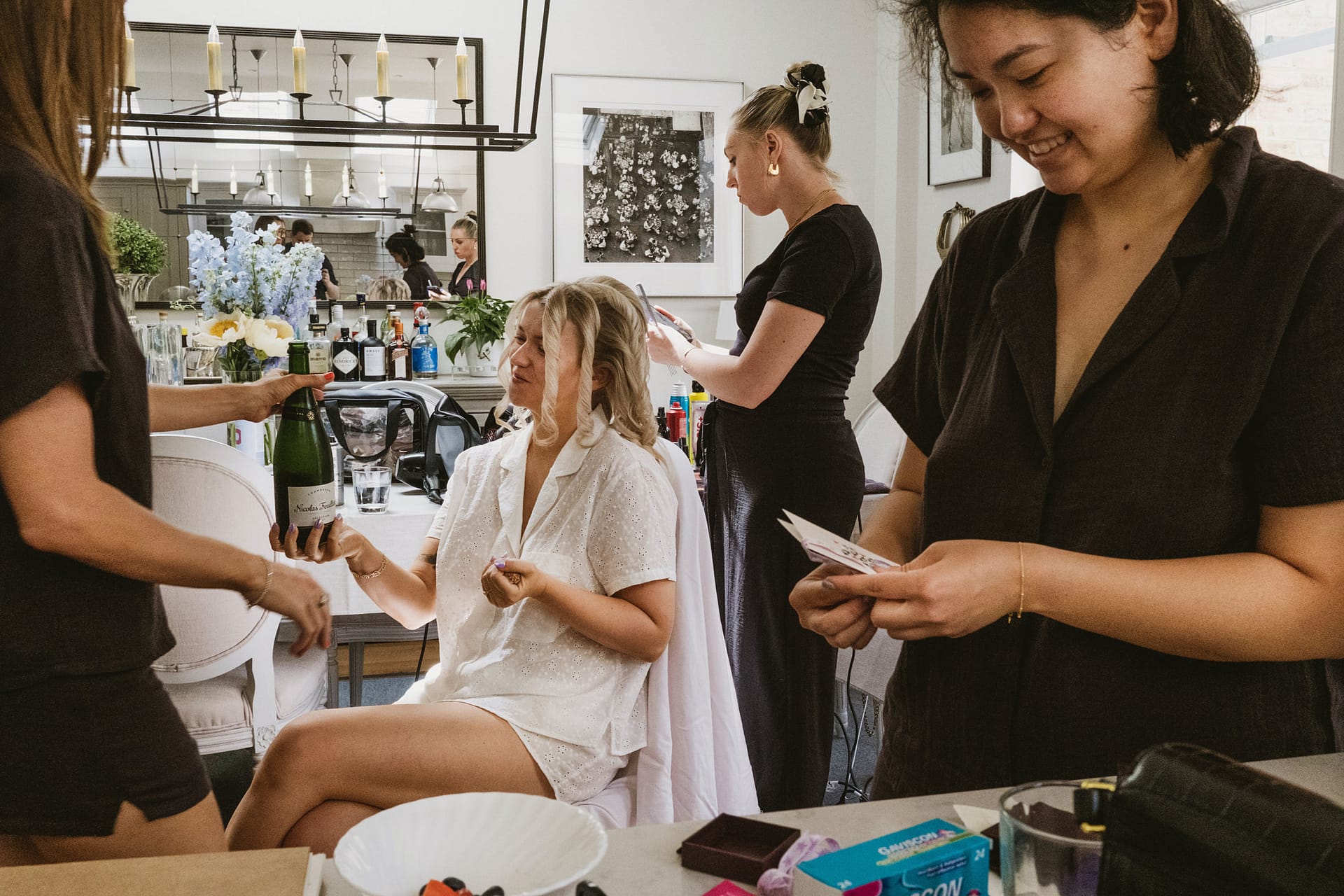 Women preparing for an event, holding champagne.