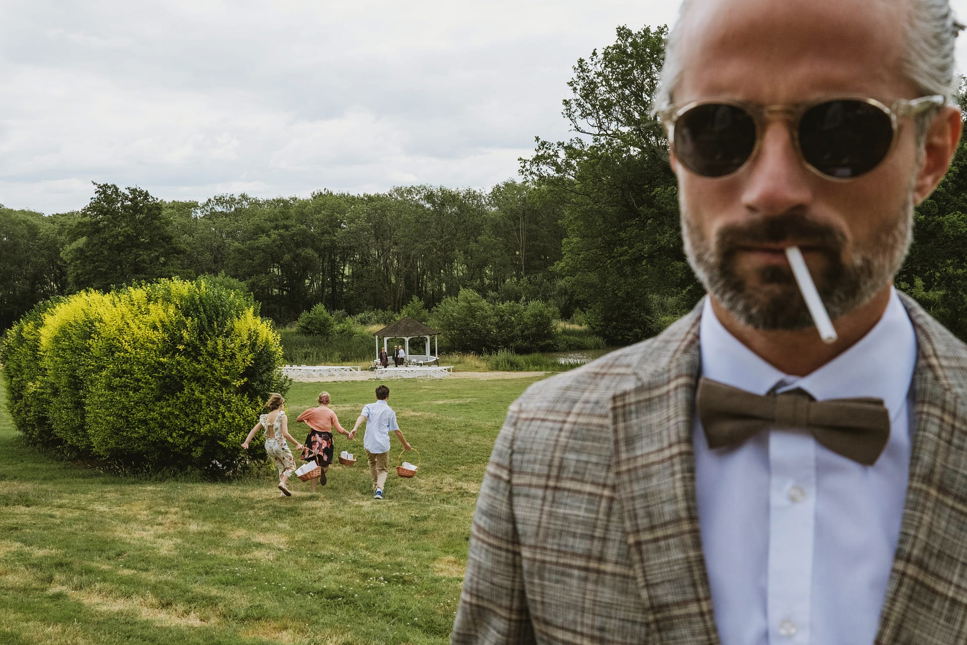 Man smoking, children running to next to the wedding ceremony at Lythe Hill Hotel