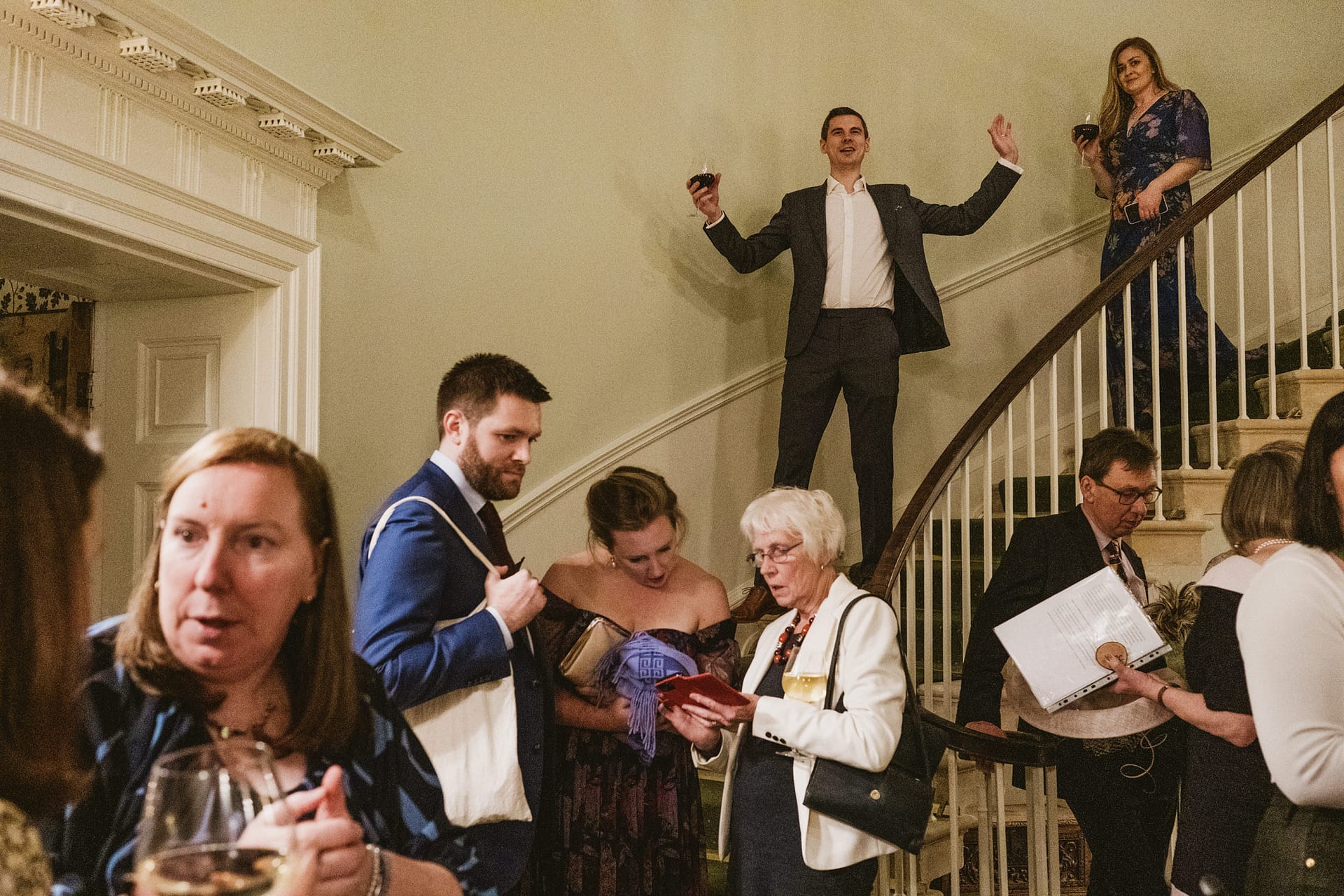 Group gathered at staircase, holding drinks and papers.