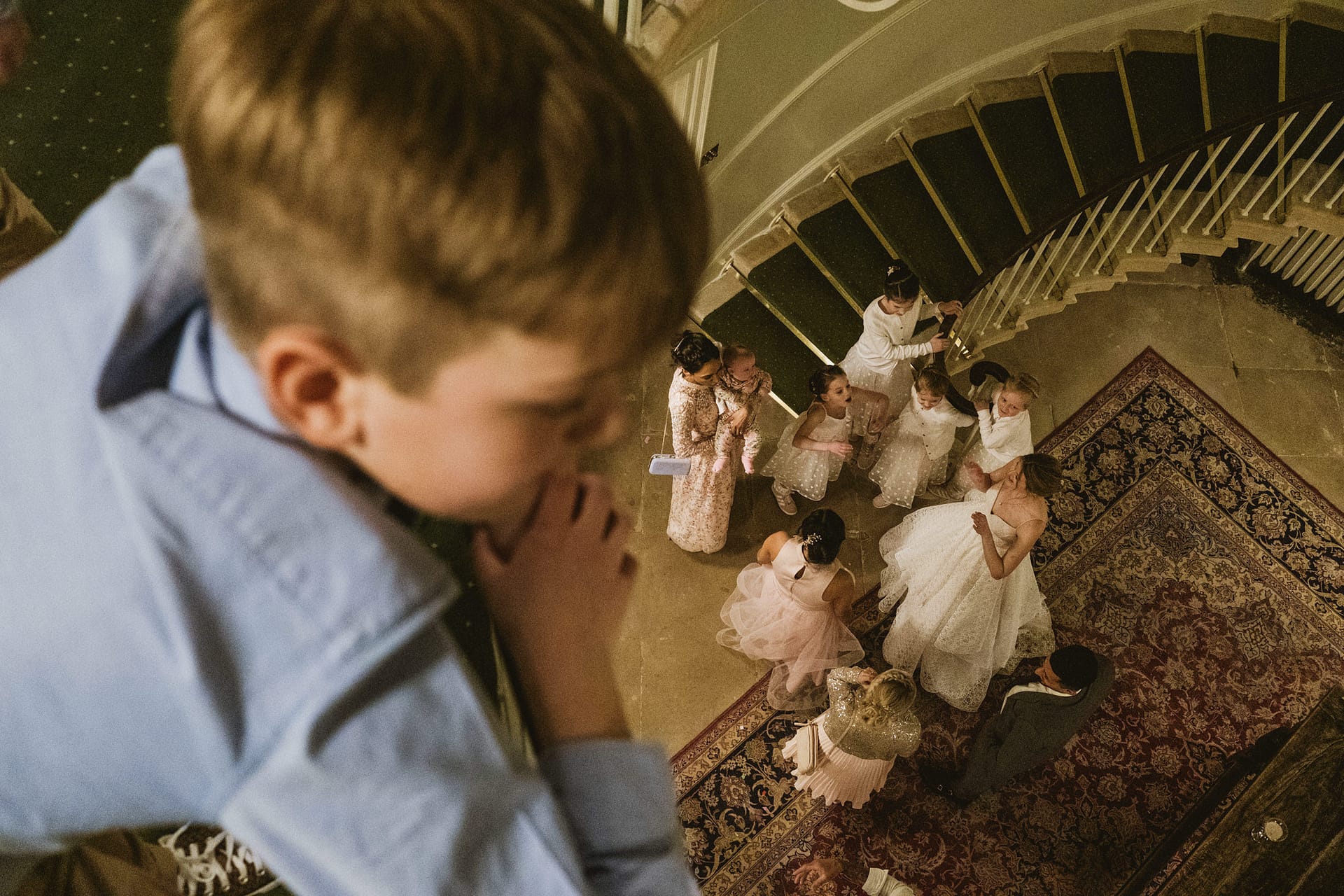 Child observing wedding guest gathering on staircase.