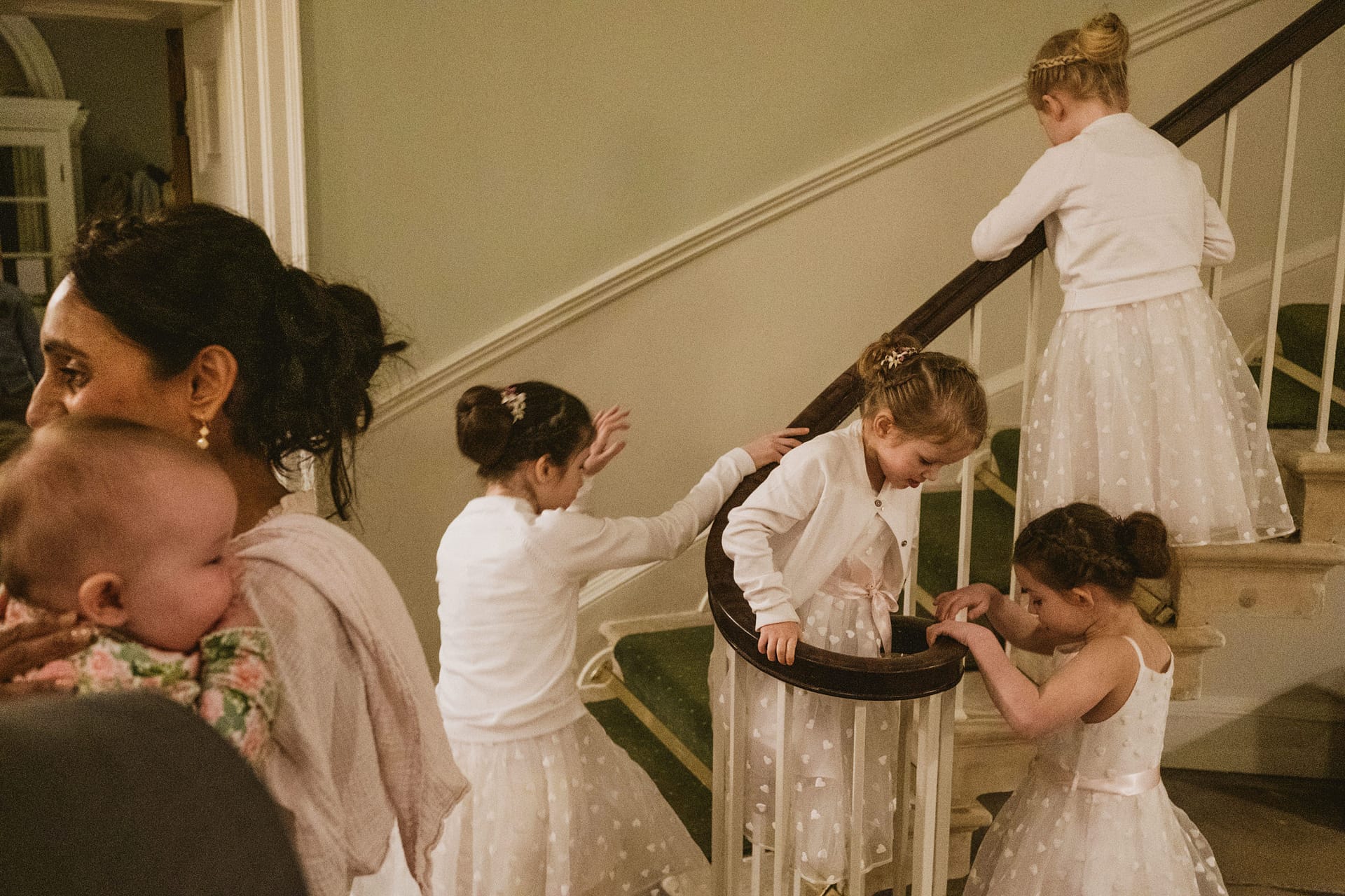 Children in white dresses on staircase.