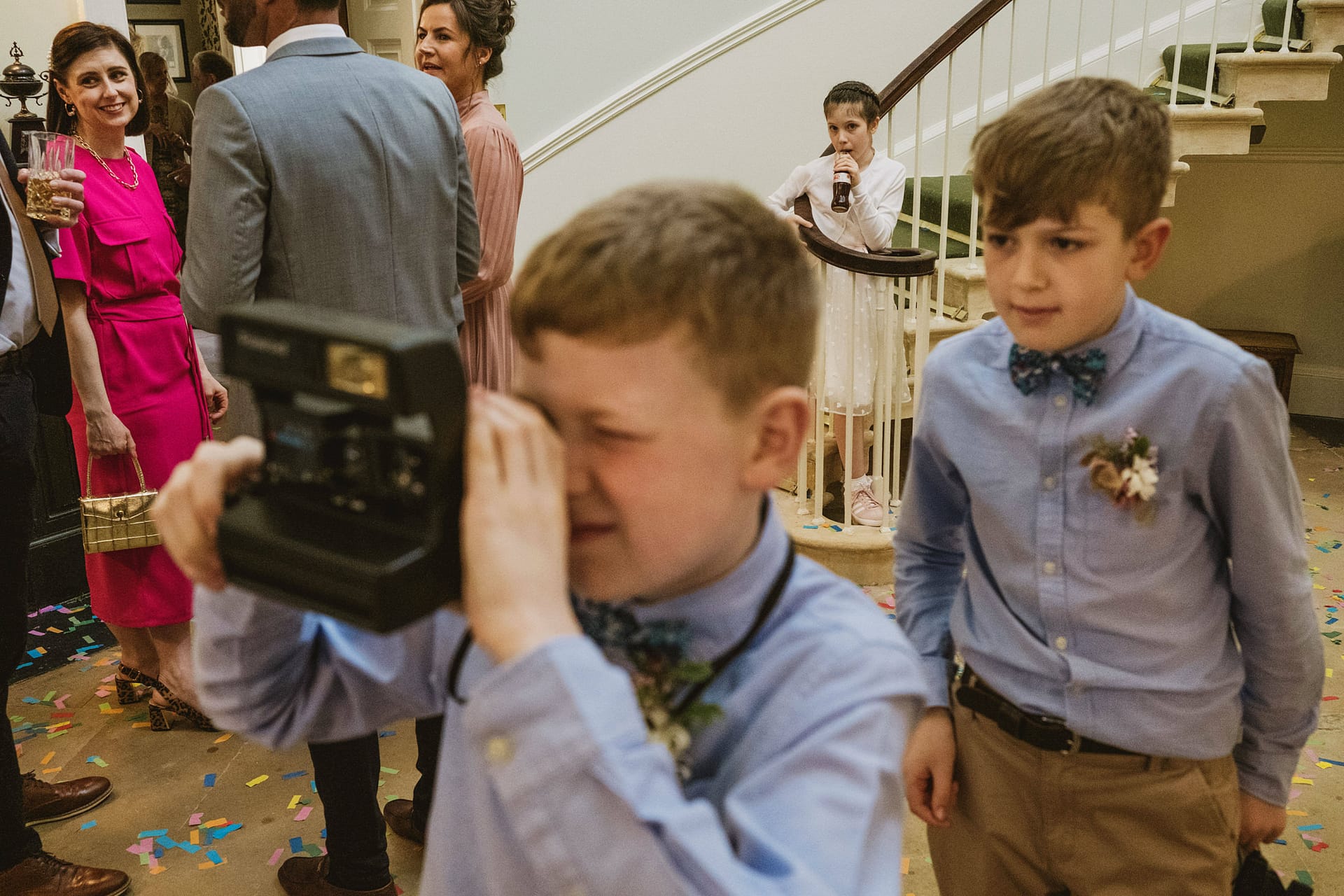 Children taking photos at lively wedding reception scene.
