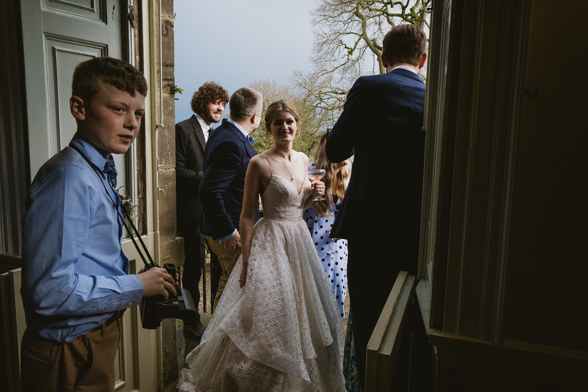 Wedding guests gather at doorway with photographer.