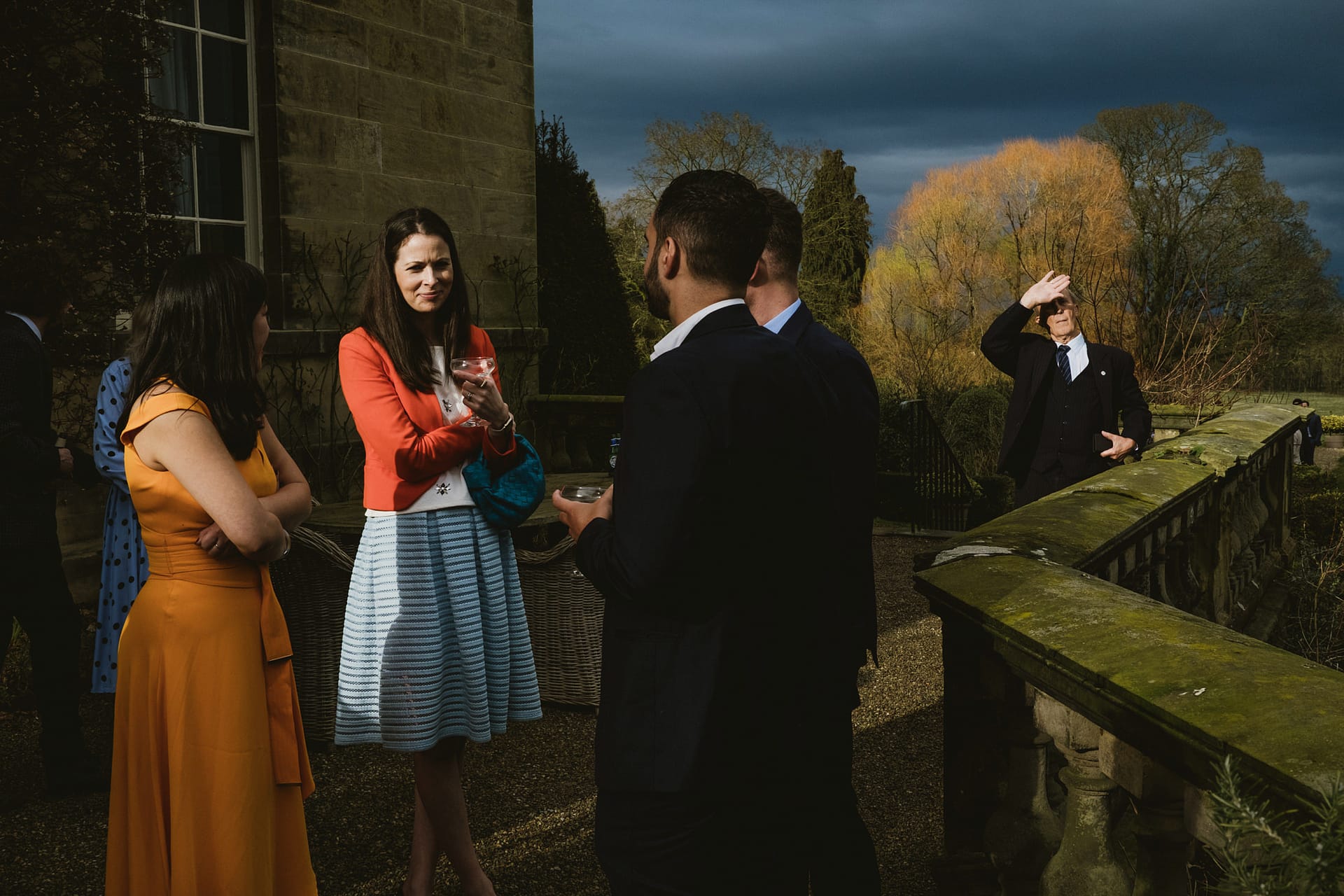 Group chatting outdoors at elegant event.