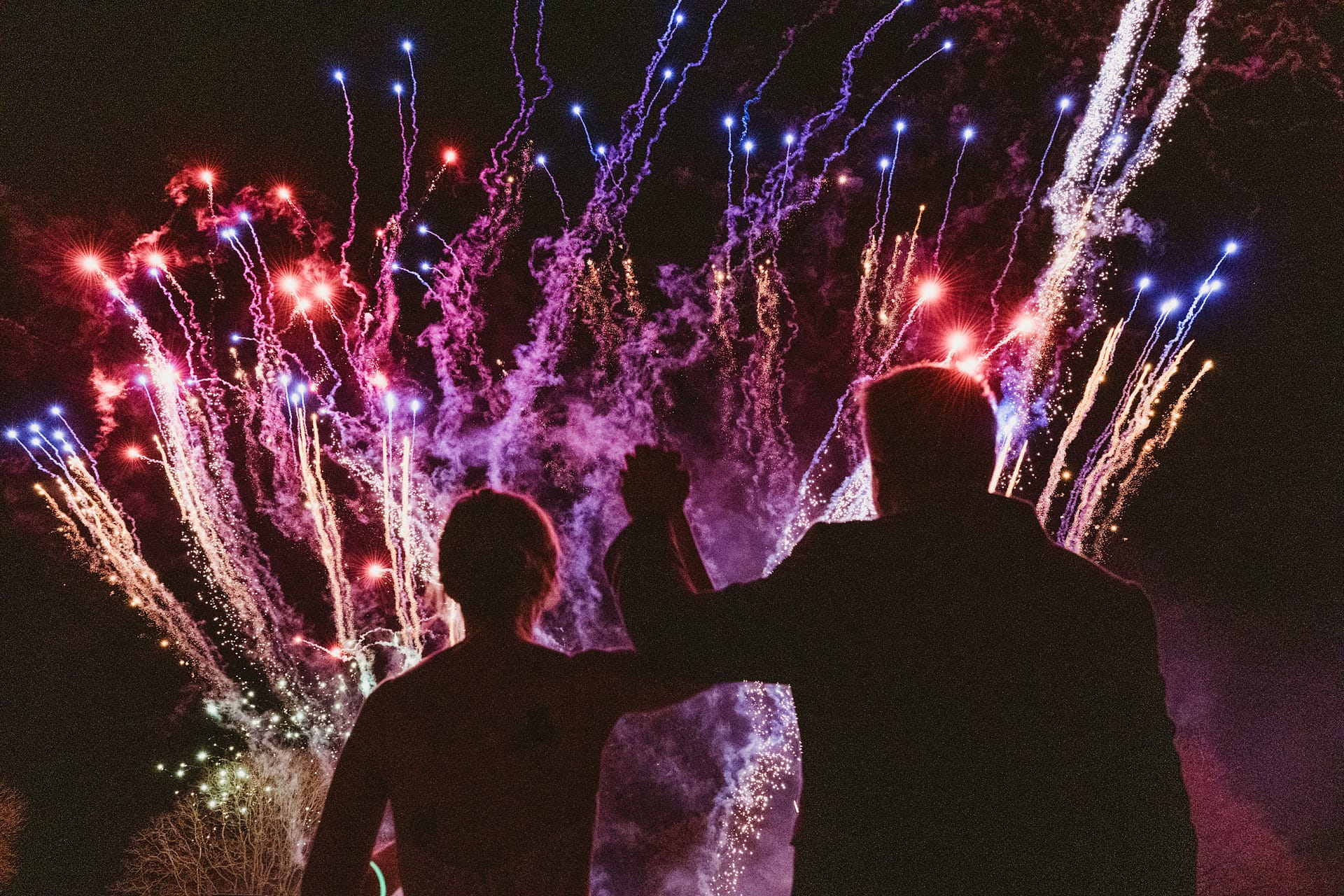 Couple watching colourful fireworks display at night.