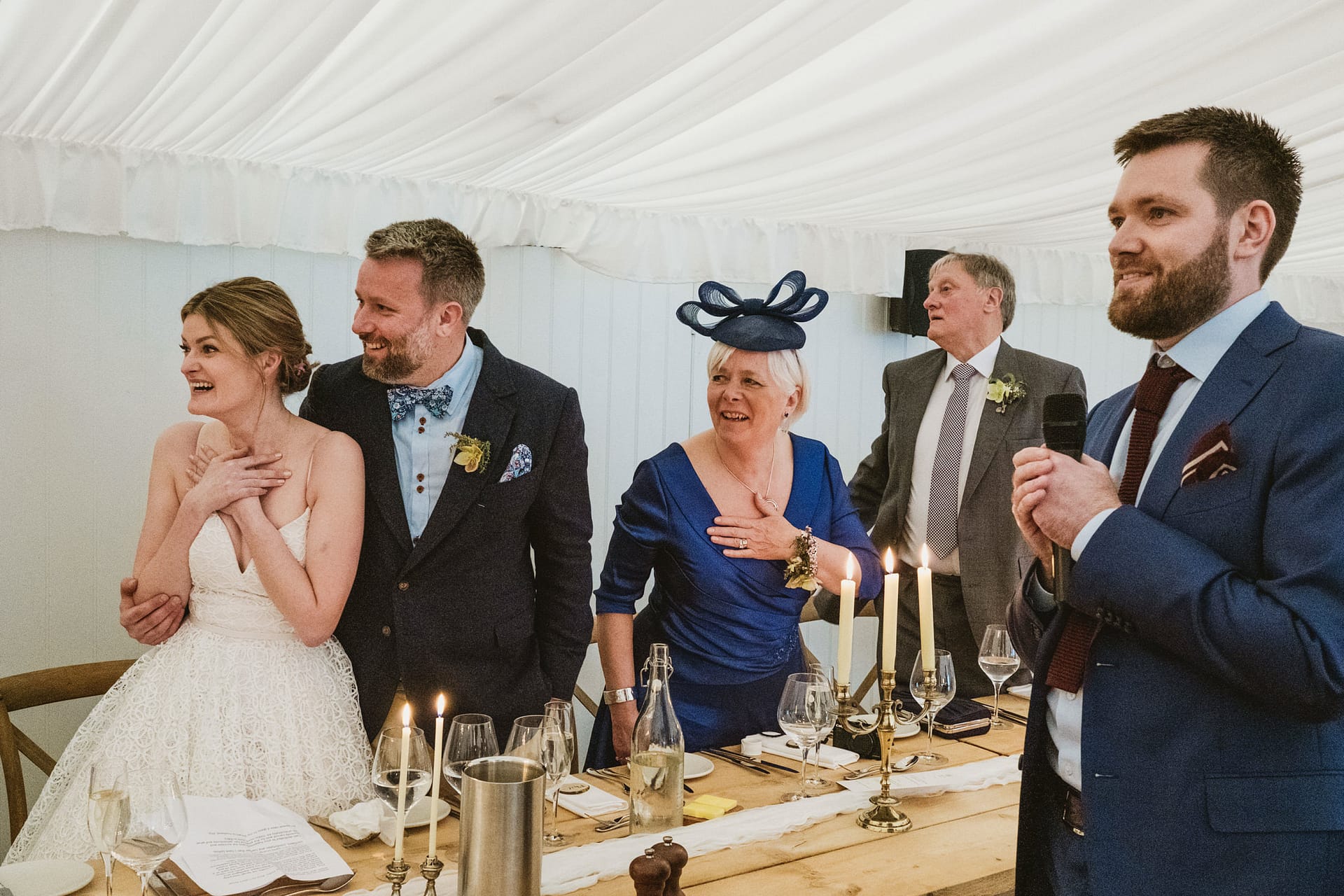 Wedding reception with speeches and guests smiling.