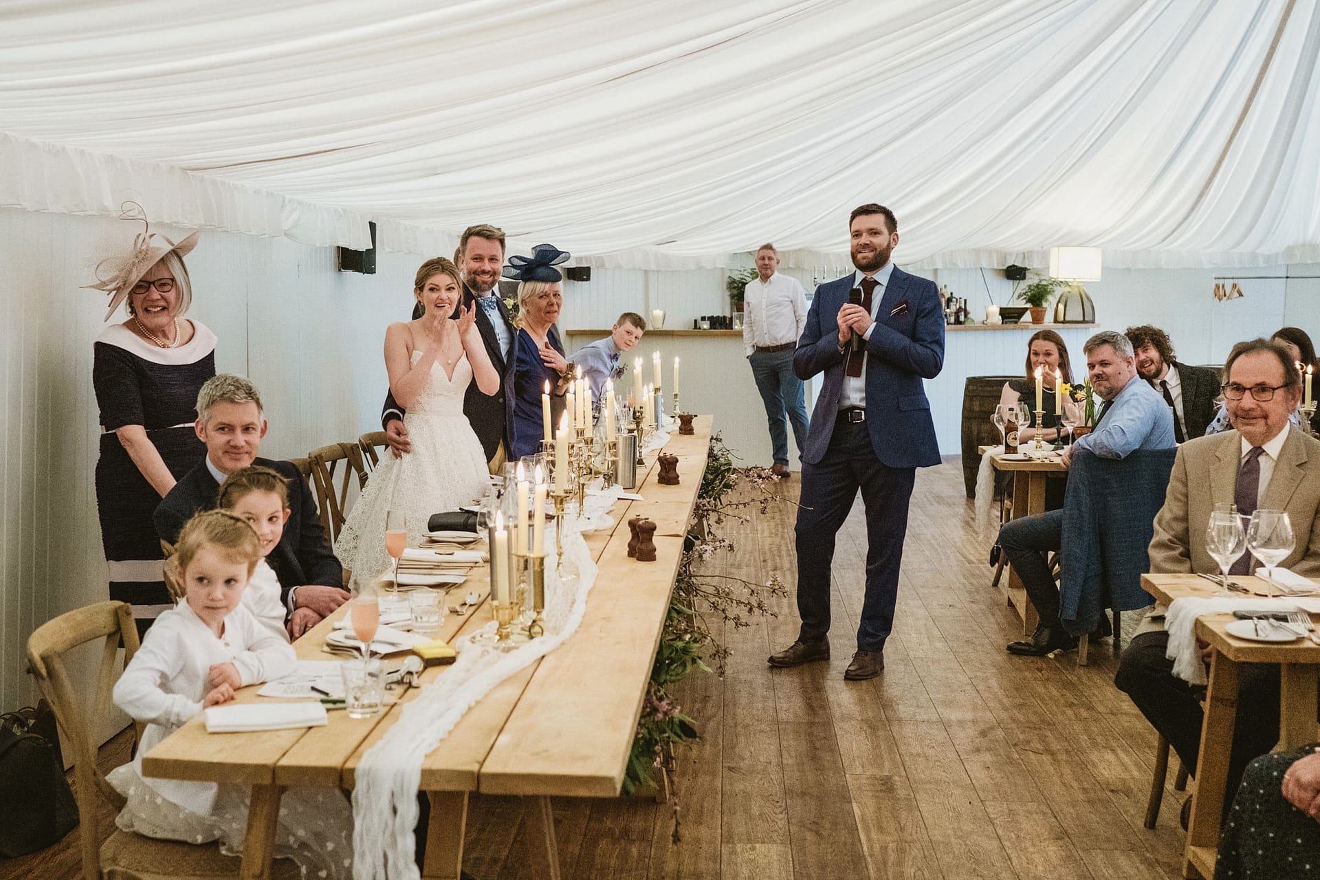 Wedding reception speech with guests at tables.