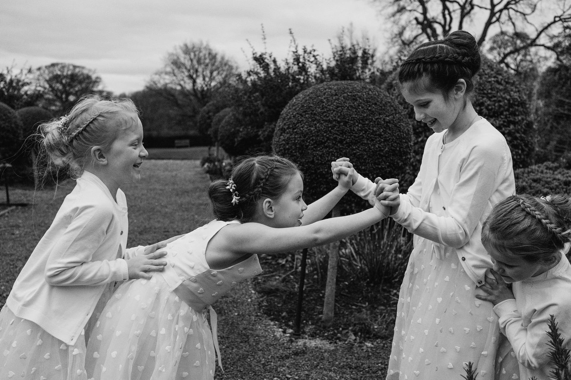 Children playing in garden, wearing matching dresses.