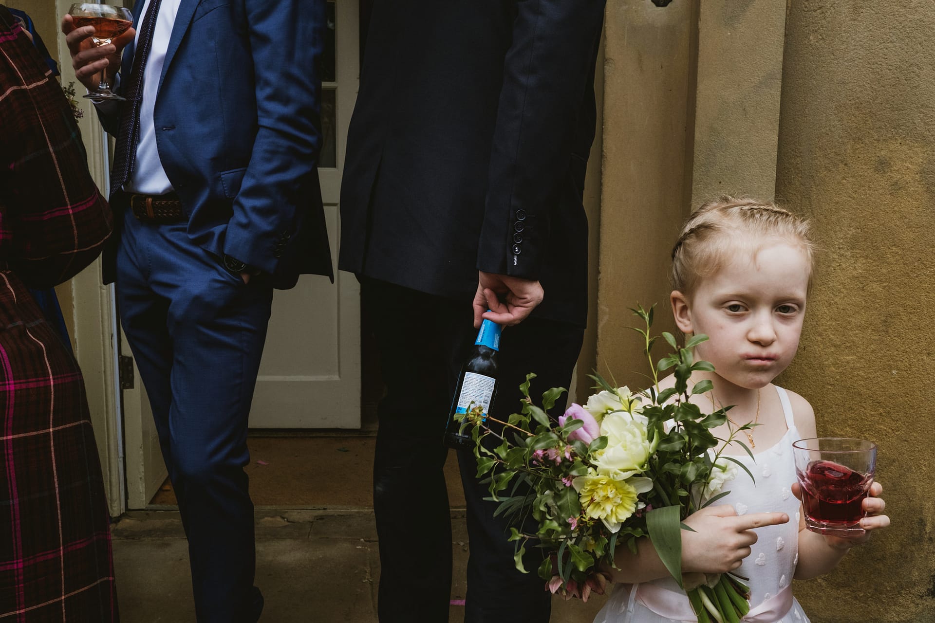 Child at wedding with drink and flowers.