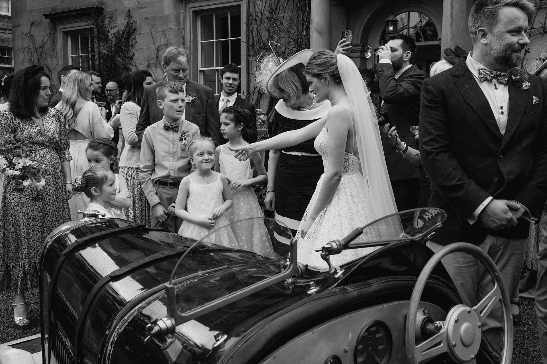 Bride greets children at outdoor wedding gathering